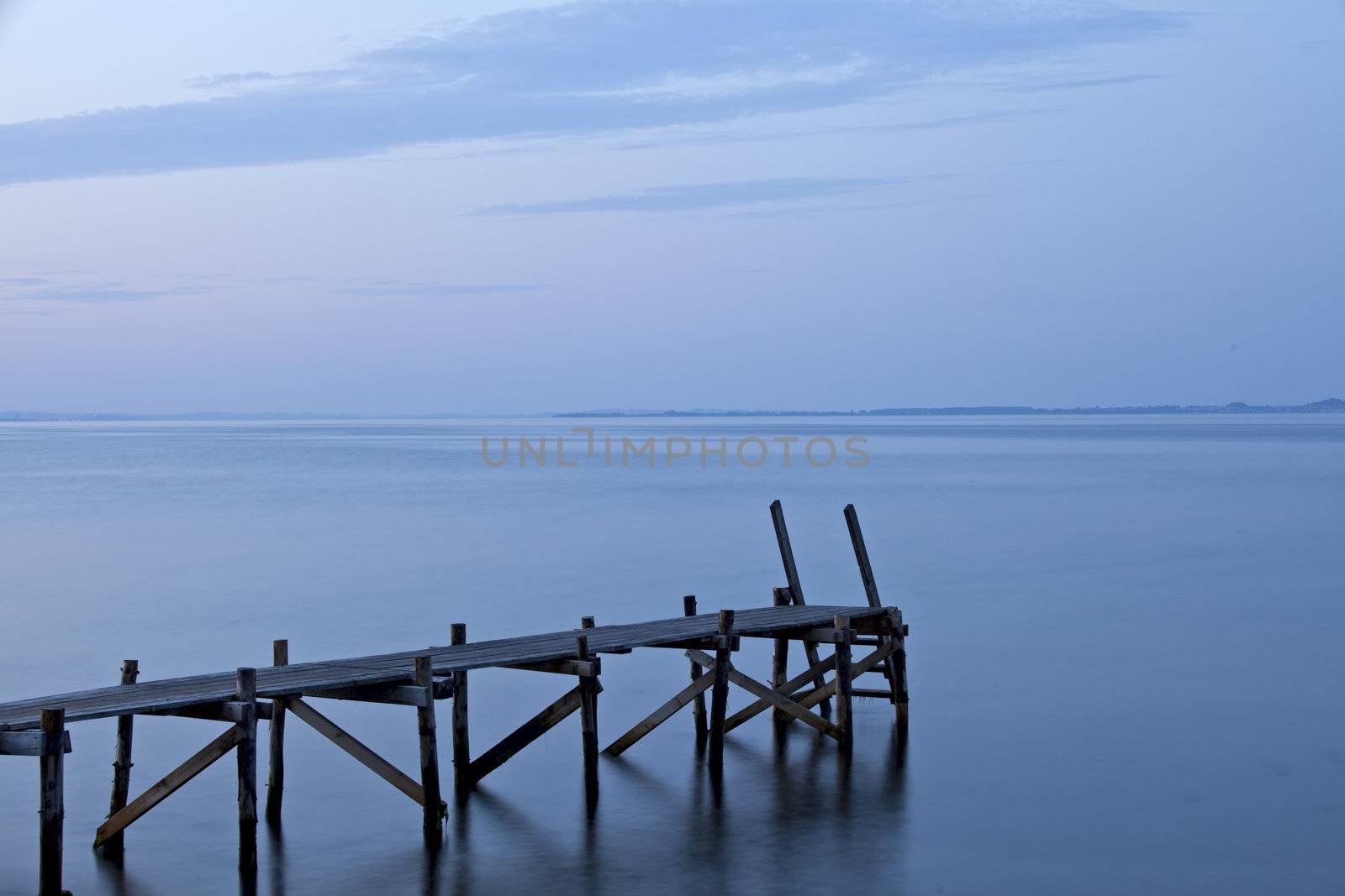 silhouette of a footbridge at the sea by bernjuer