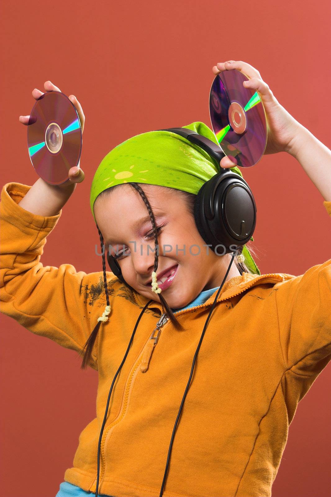 little pretty child listening music in headphones and holding two CD 