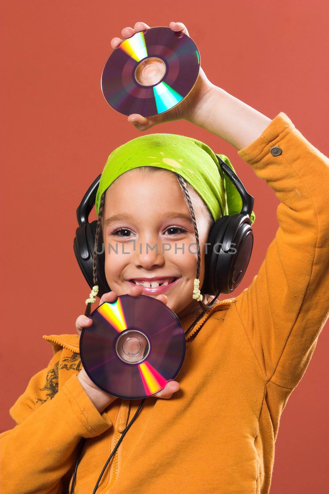 little pretty child listening music in headphones and holding two CD 