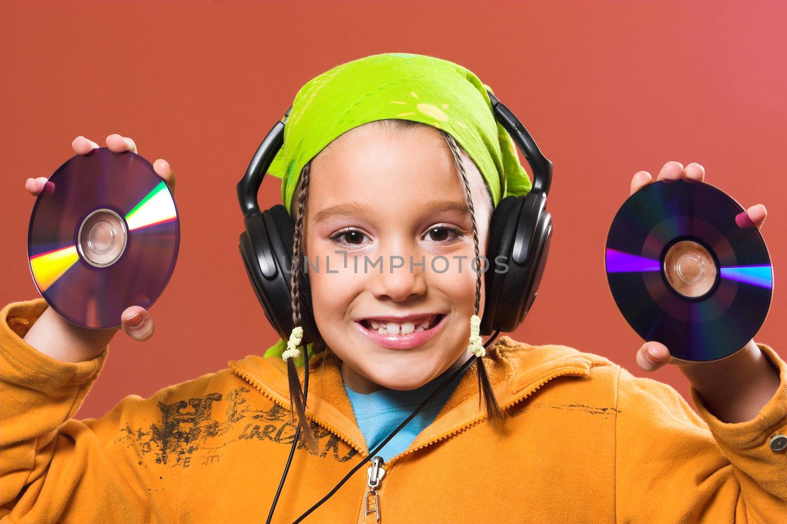 little pretty child listening music in headphones and holding two CD 