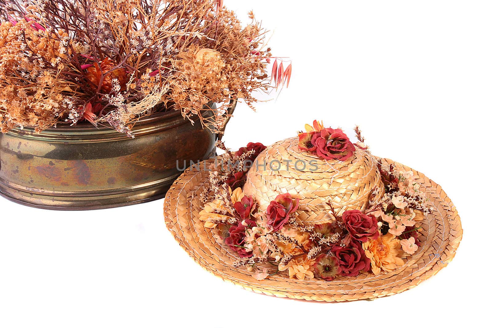 Straw hat with autumn colours and a metal vase with an autumn dry bouquet.