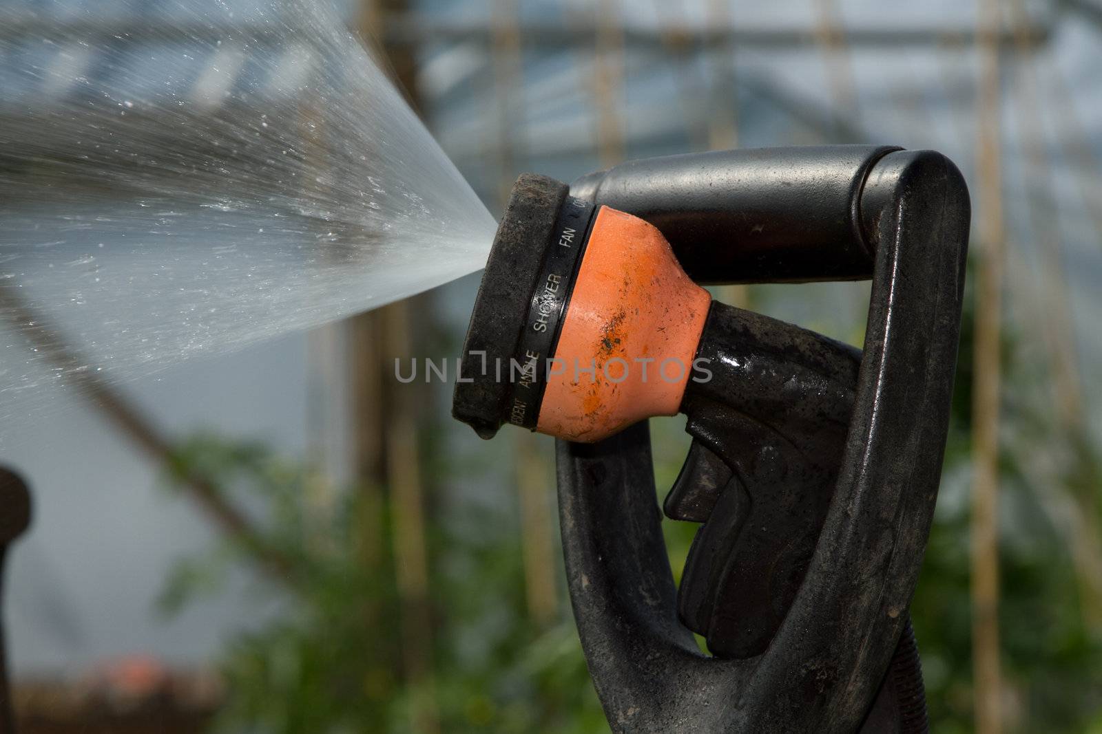 A hose head wedged into the handle of a fork for support with spraying water.