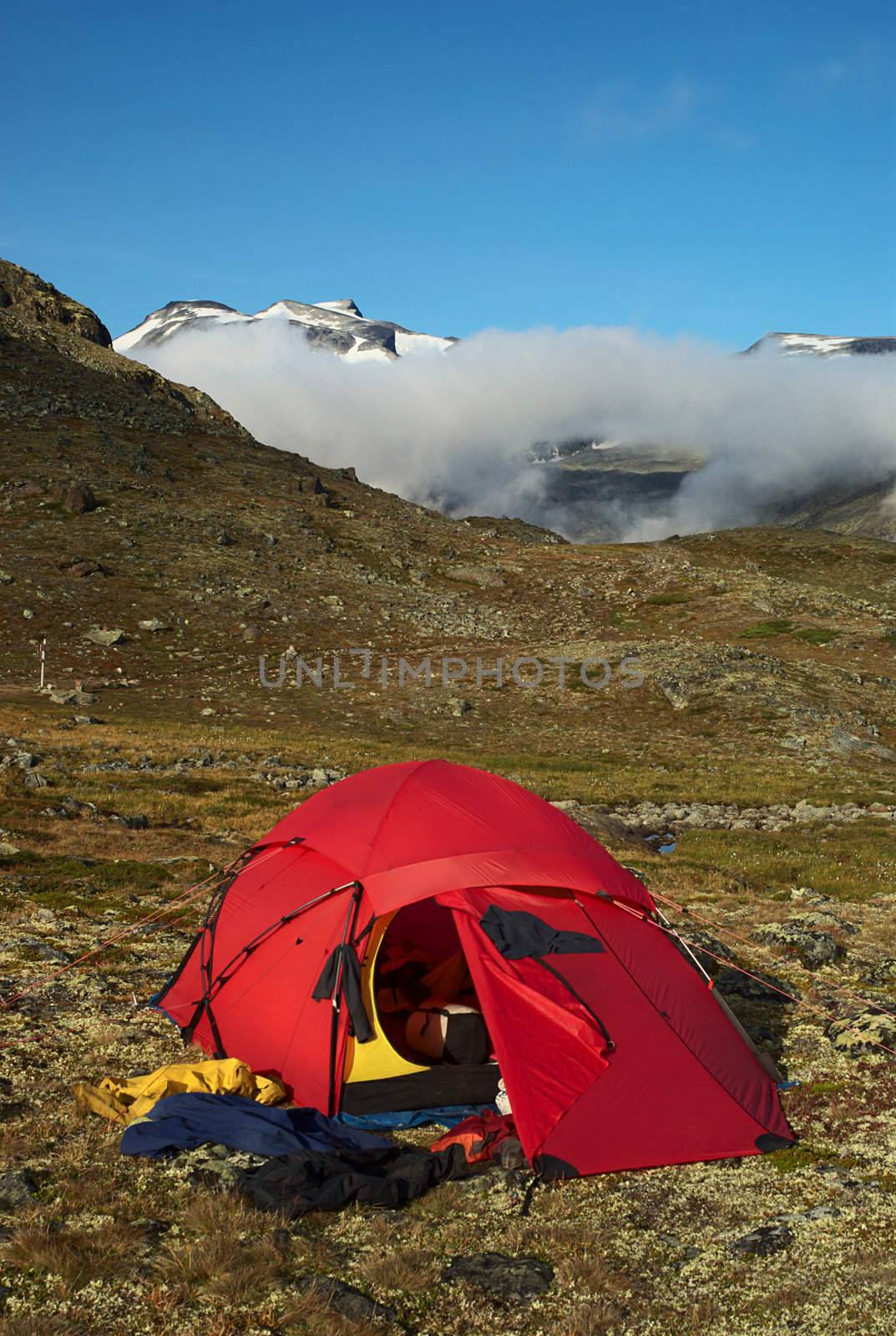 Tent and drying clothes in the Jotunheimen National Park, Norway with the Galdhopiggen covered by clouds in the back 