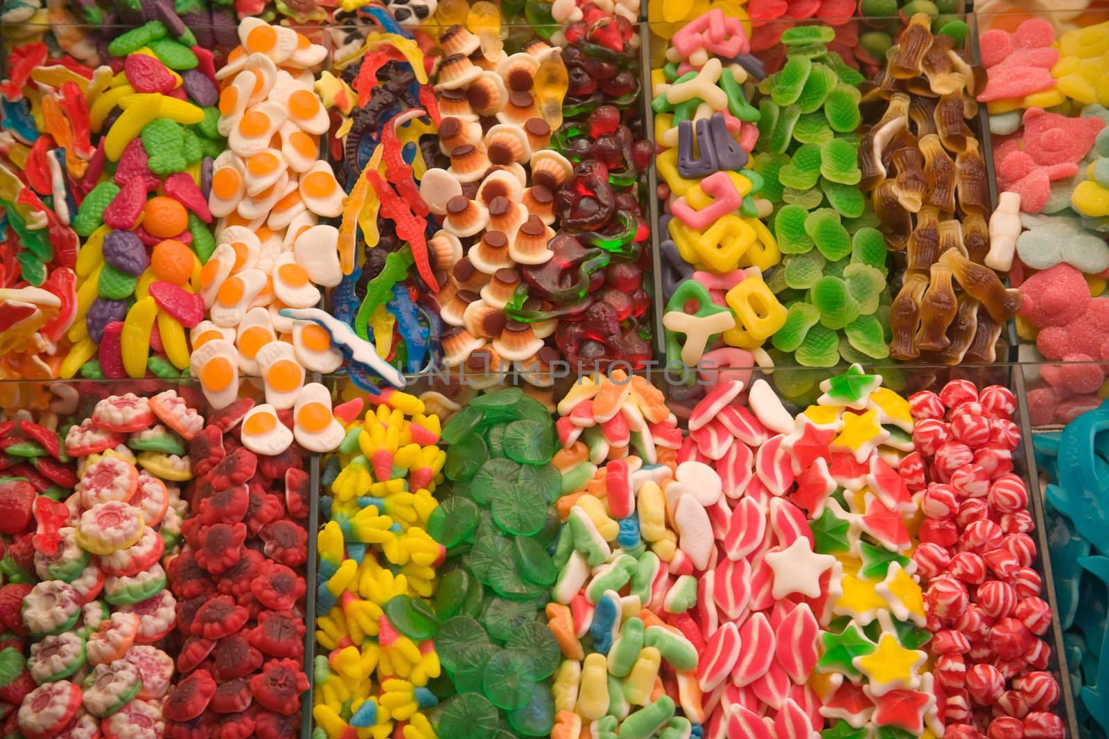 Assortment of sweets and candies on lots of shapes and colours at a market stall.