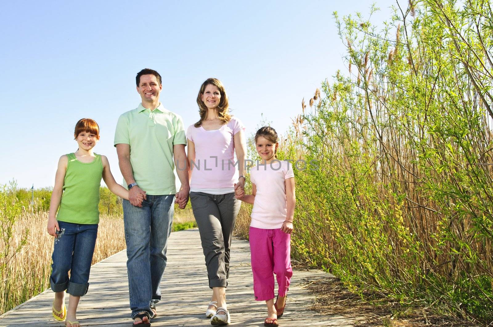 Portrait of happy family of four walking on boardwalk