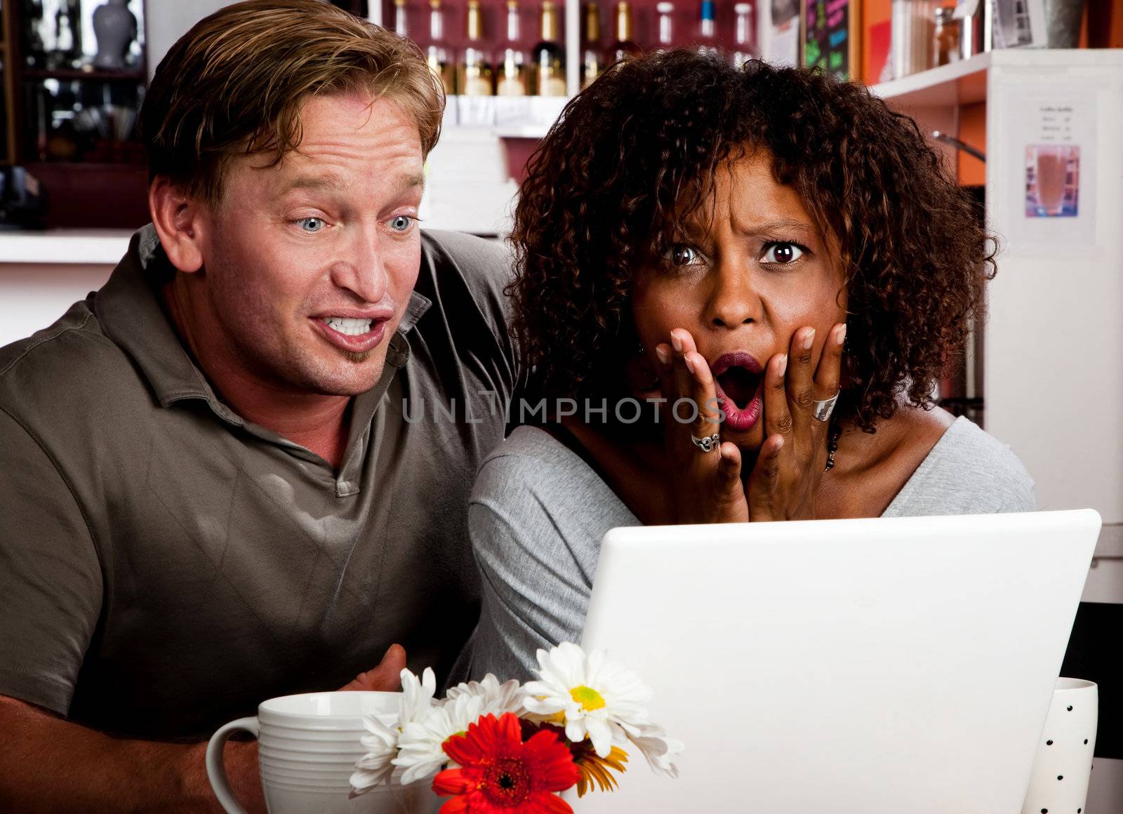 Mixed race couple in coffee house with laptop computer by Creatista
