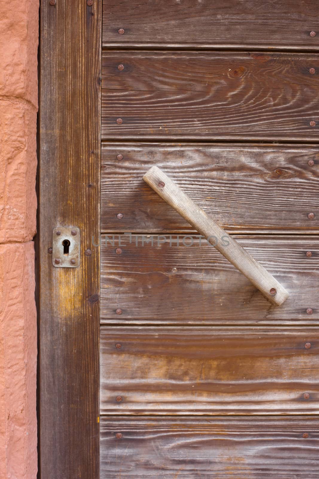 Old locked wooden door with key-hole and simple handle.