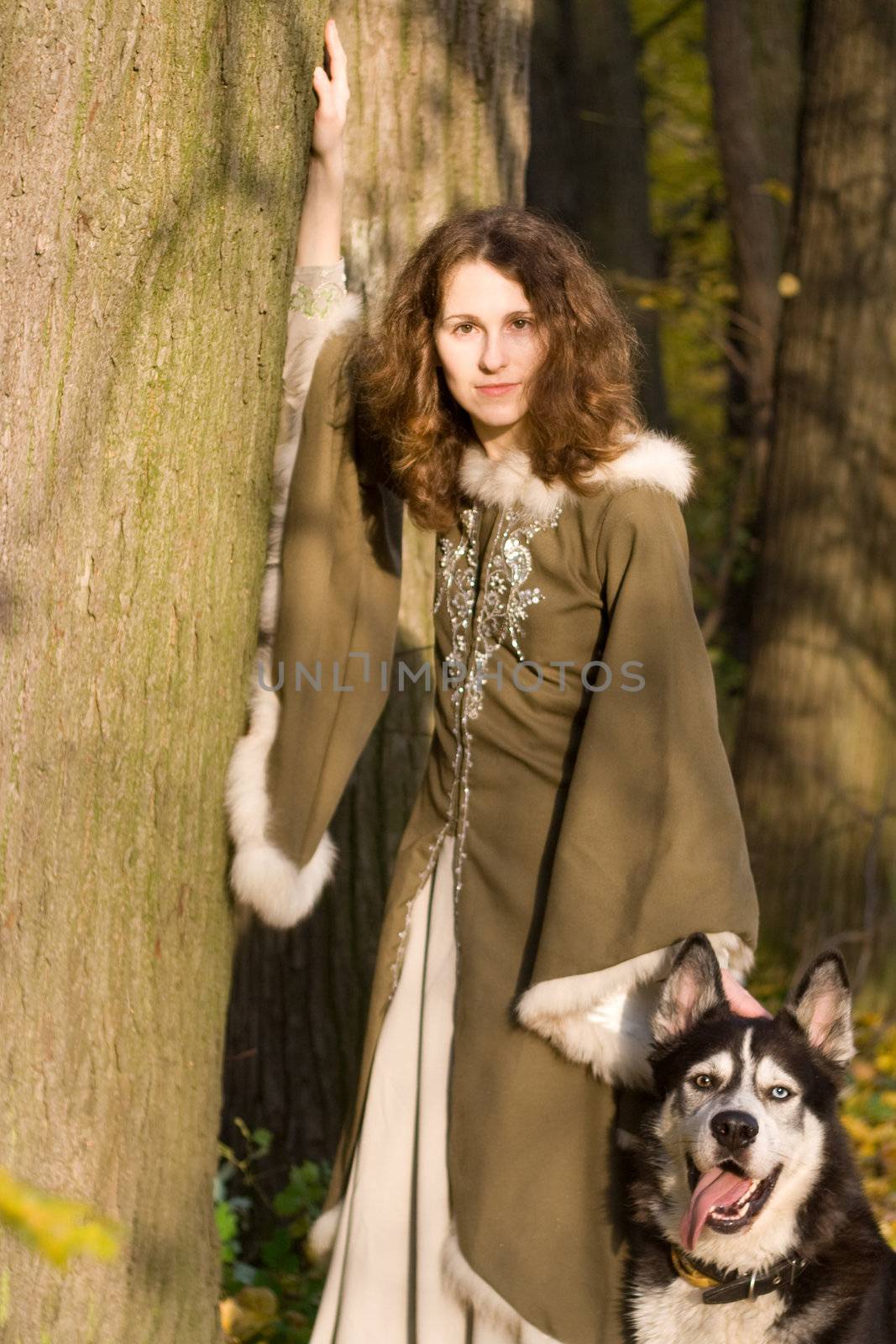 Lady in medieval dress and dog in the forest
