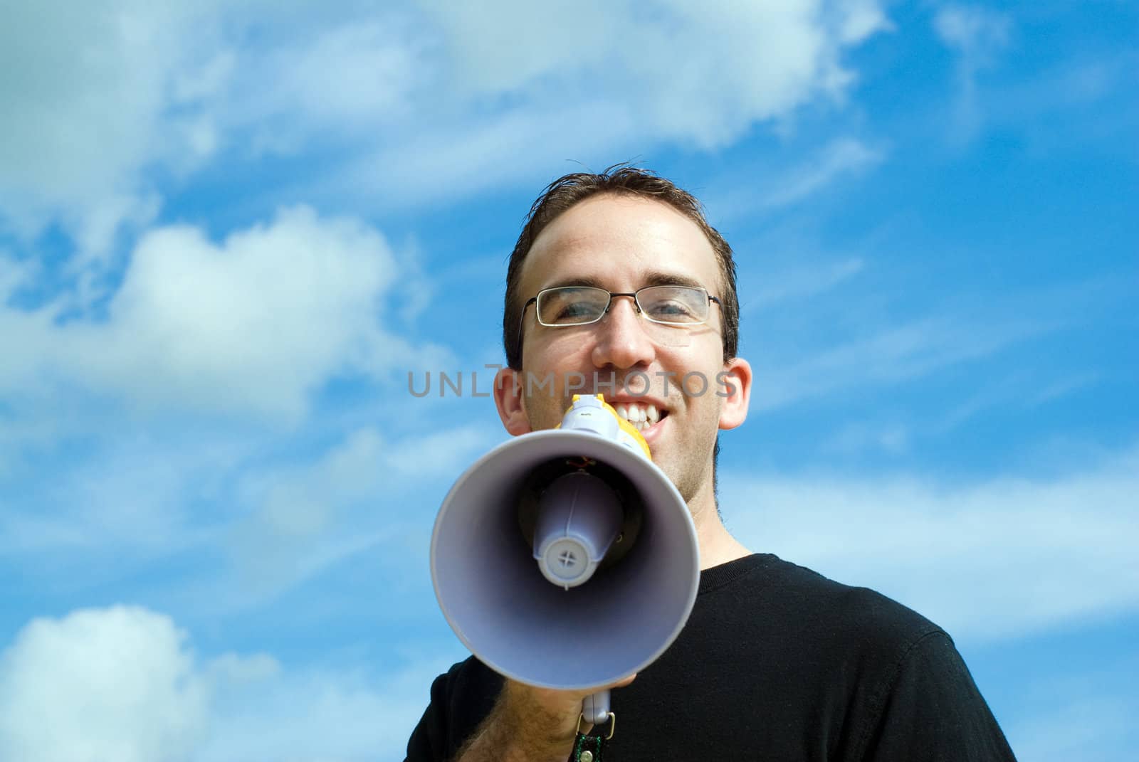 A man making an announcement with a megaphone with a blue sky behind him