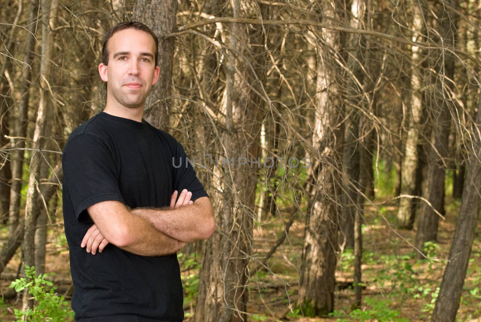 A young man standing in the forest with copyspace to the right