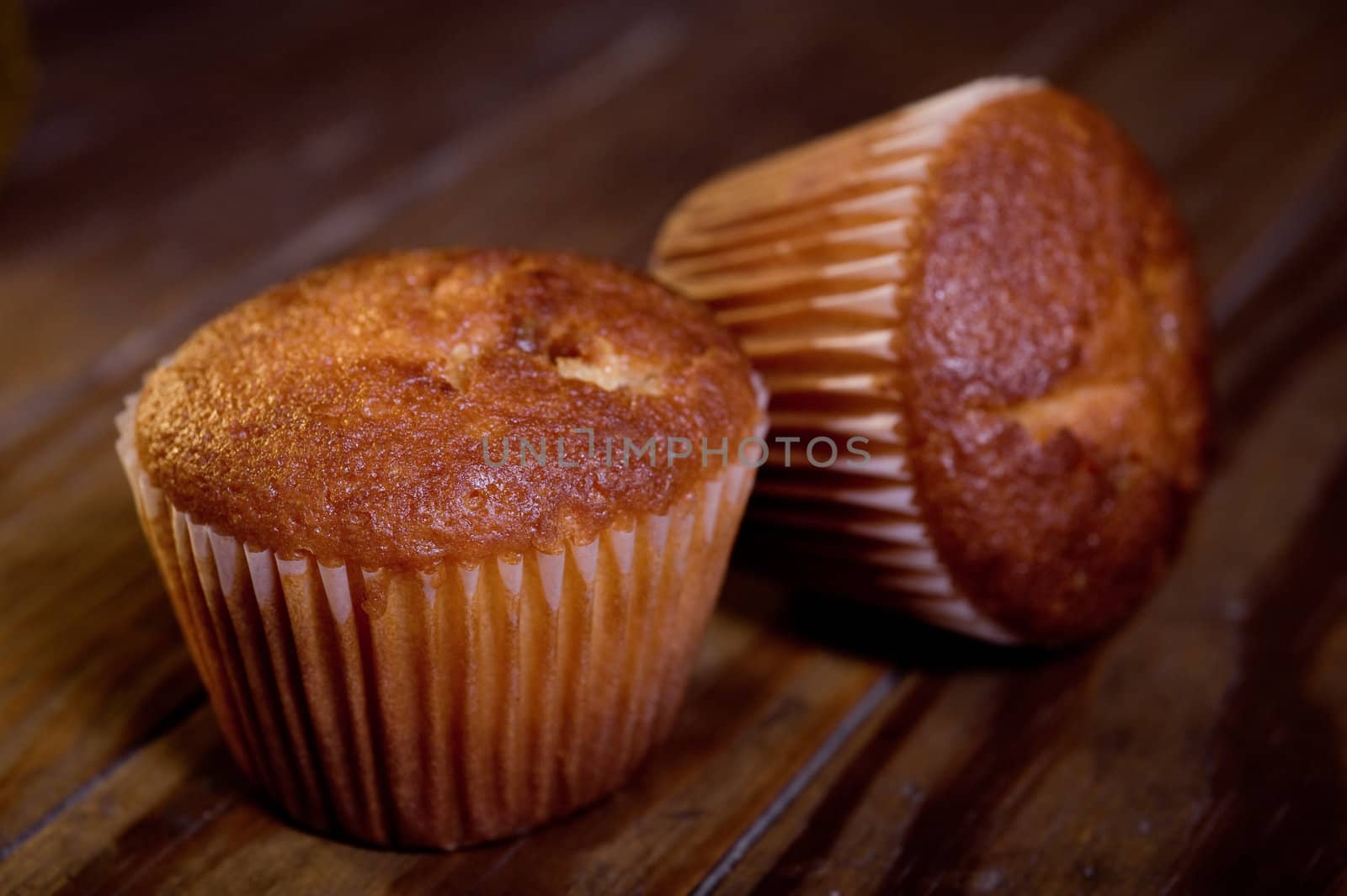 Two muffins on wooden table, close up, studio shot.
