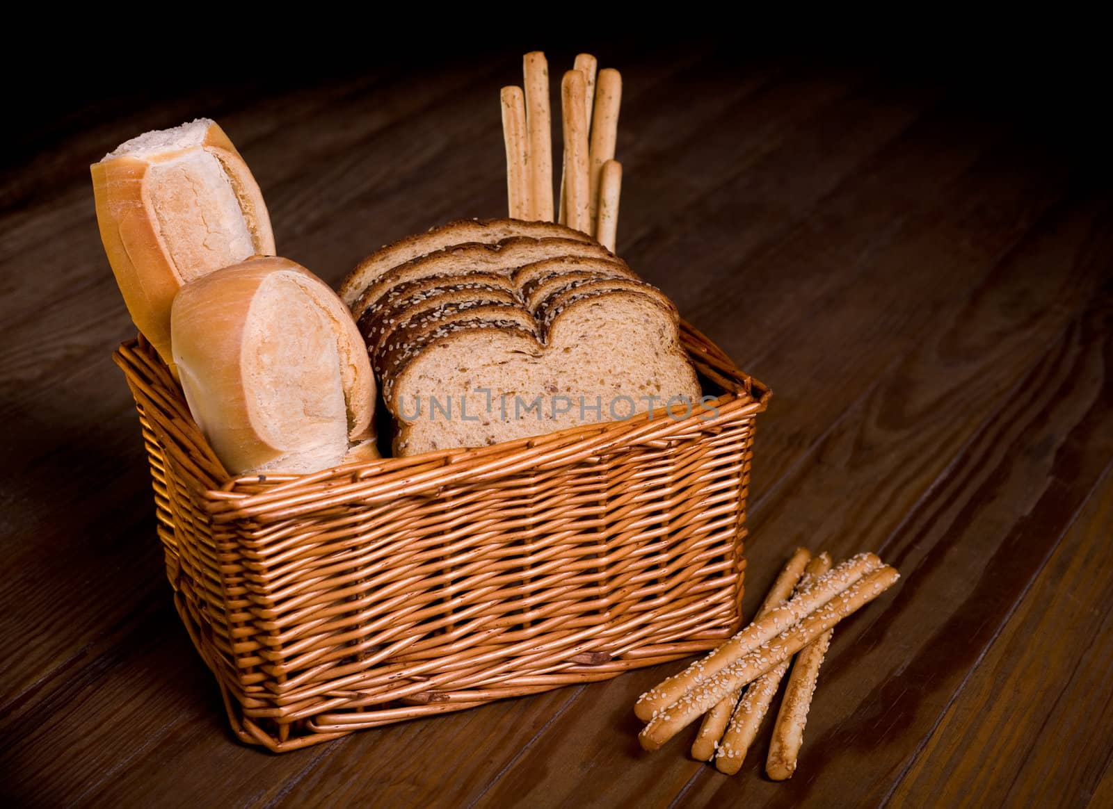 Basket with assorted bread on a wooden table.
