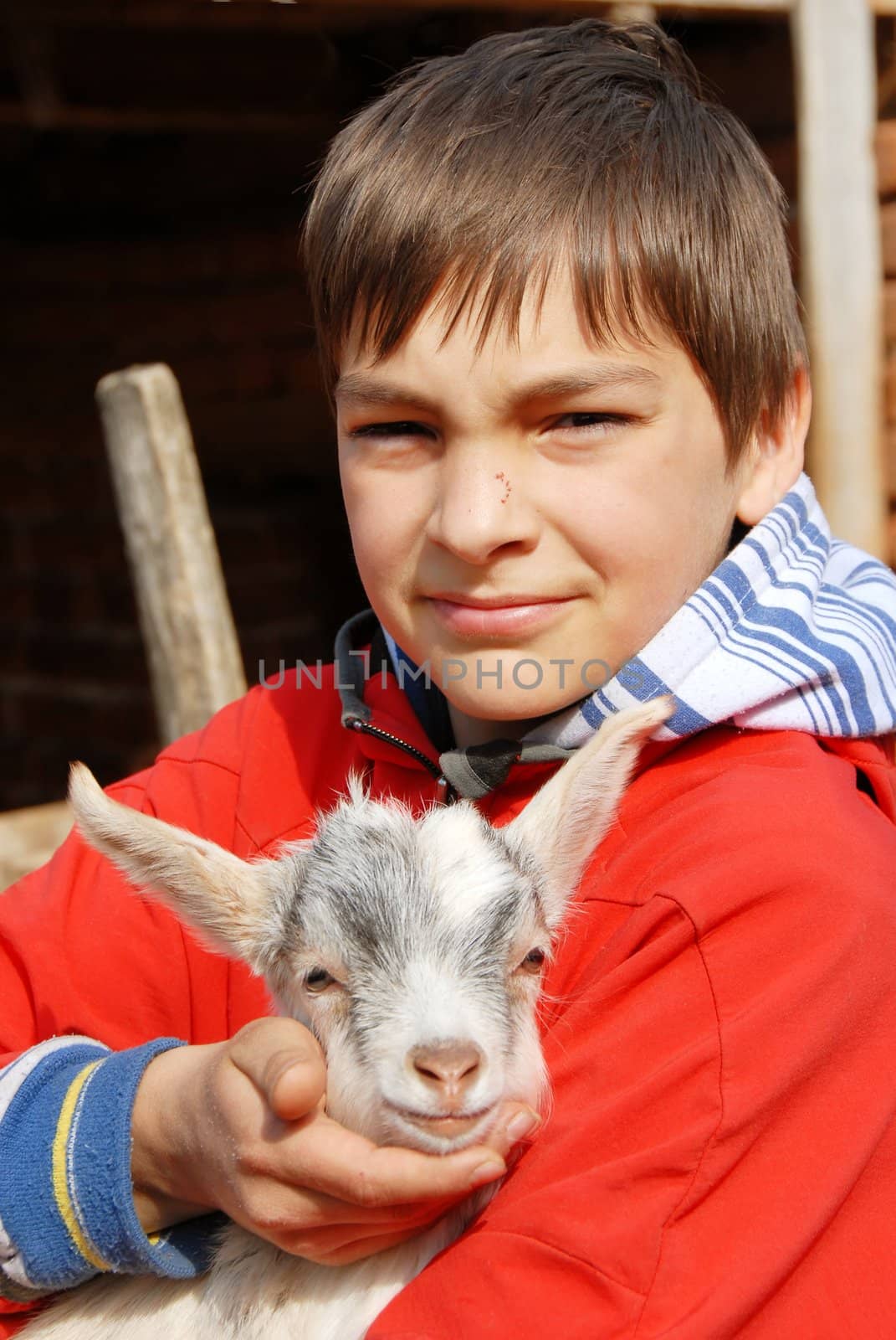 teenage boy portrait outdoors with little goat in hands