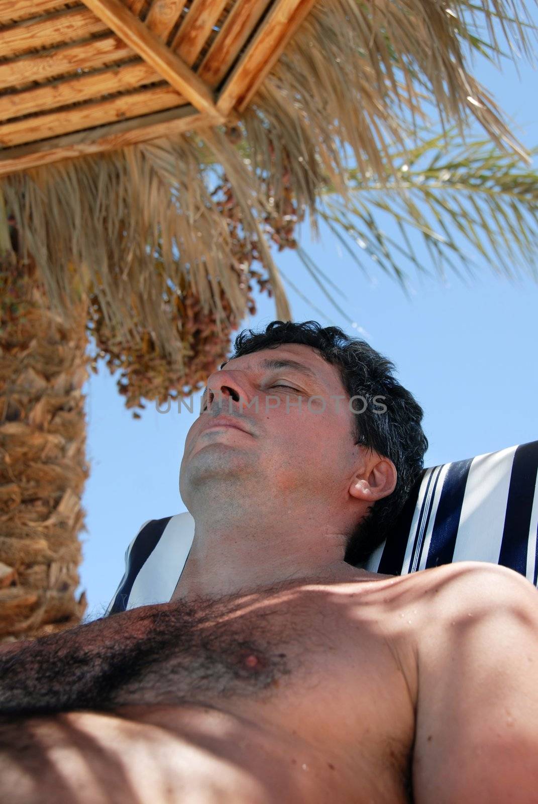 caucasian man portrait lying under sunshade on beach in Egypt