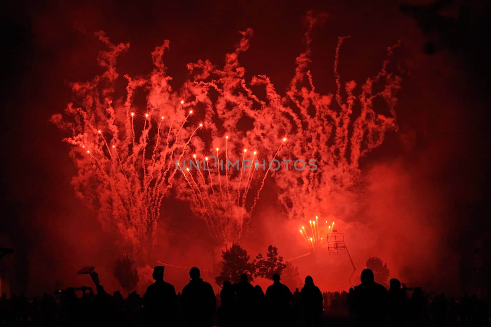 Red fireworks with people silhouettes in foreground