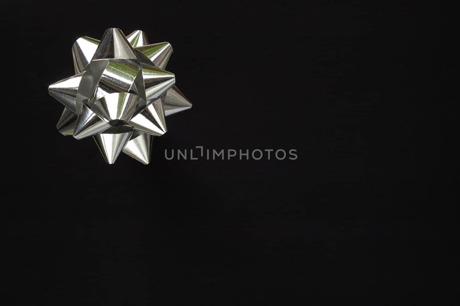 A decorative star, made from silver ribbon, on a pure black background with space for text (copy).