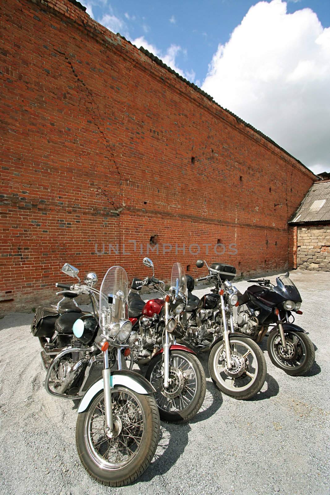 Motorcycles at a brick wall on a background of the sky