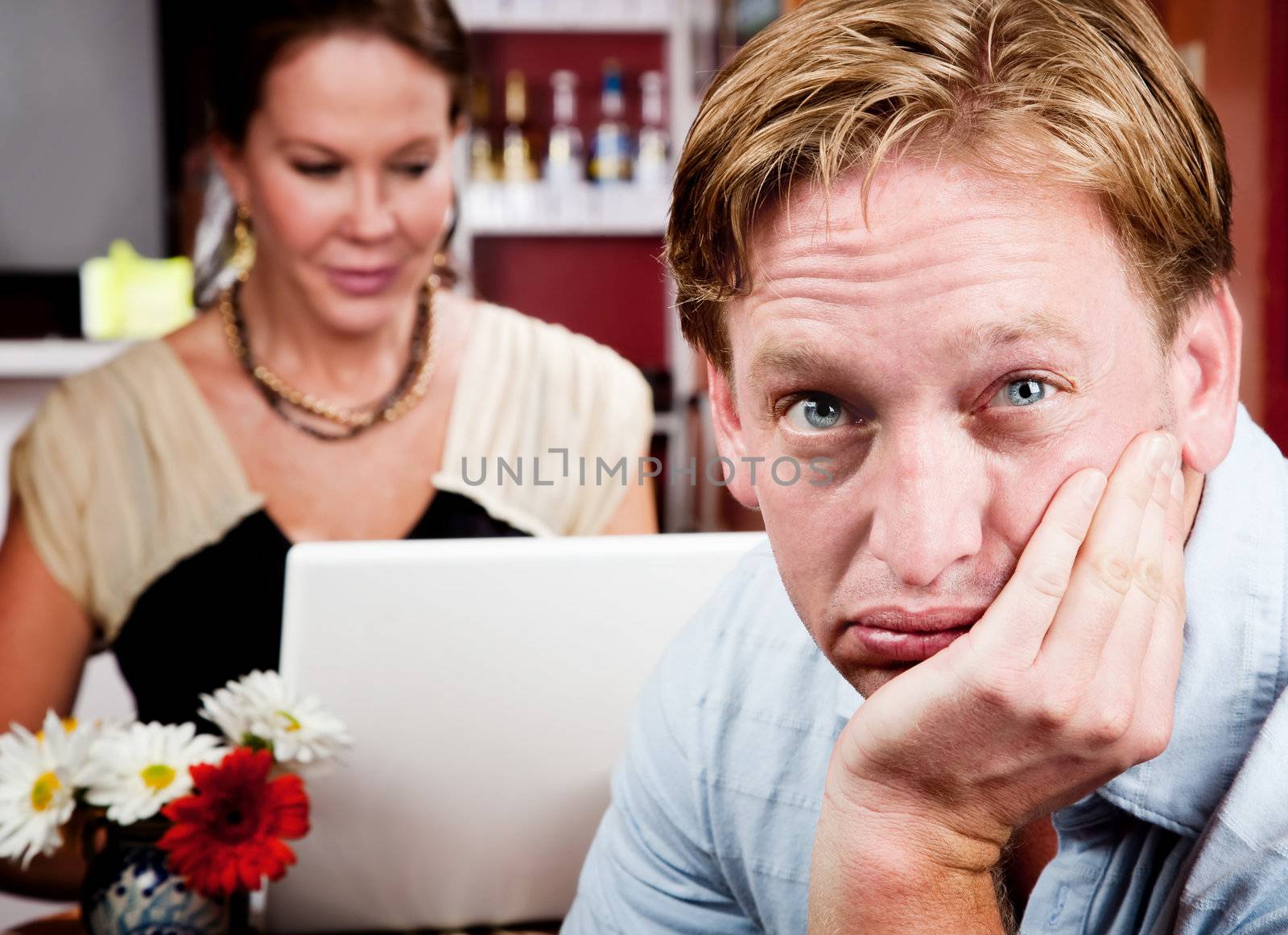 Bored man with woman on laptop computer in coffee house