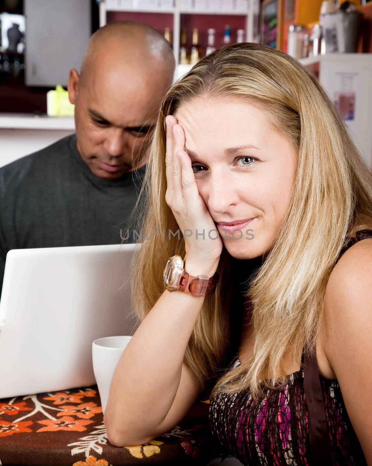 Bored woman with man on laptop computer in coffee house