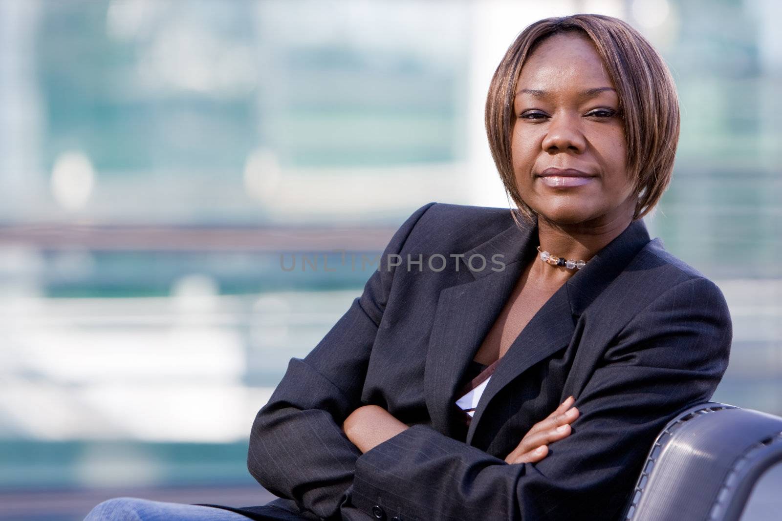 Black african american business woman posing in front of a modern office building with arms folded