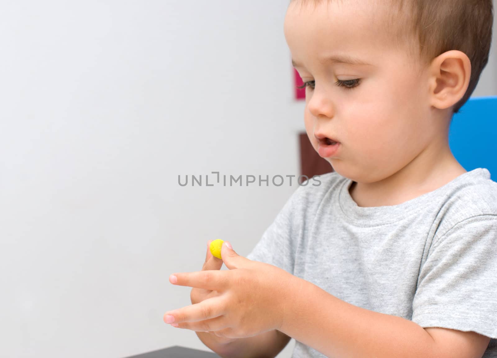 Boy play with yellow plasticine