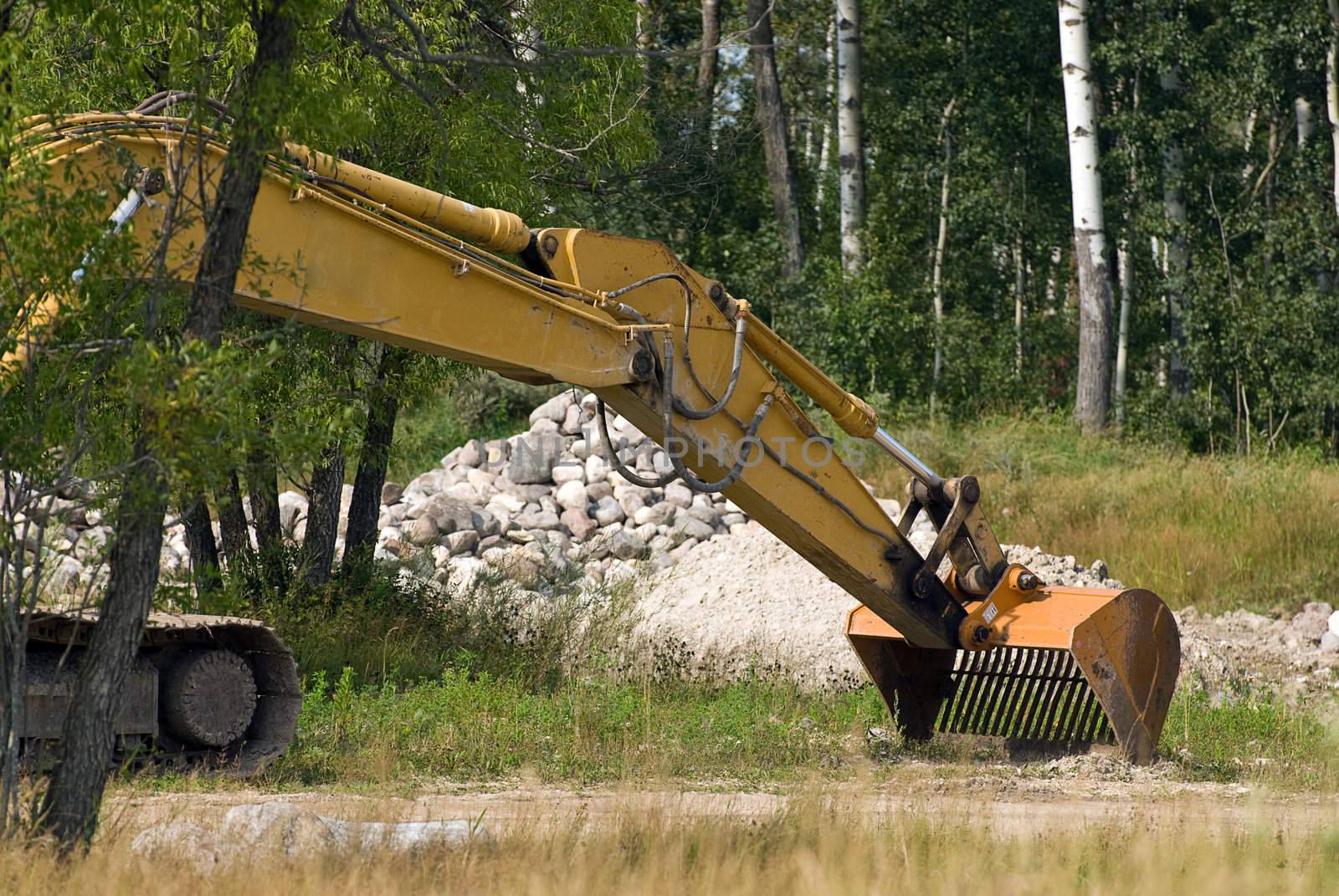 An excavator shovel with a pile of stones behind