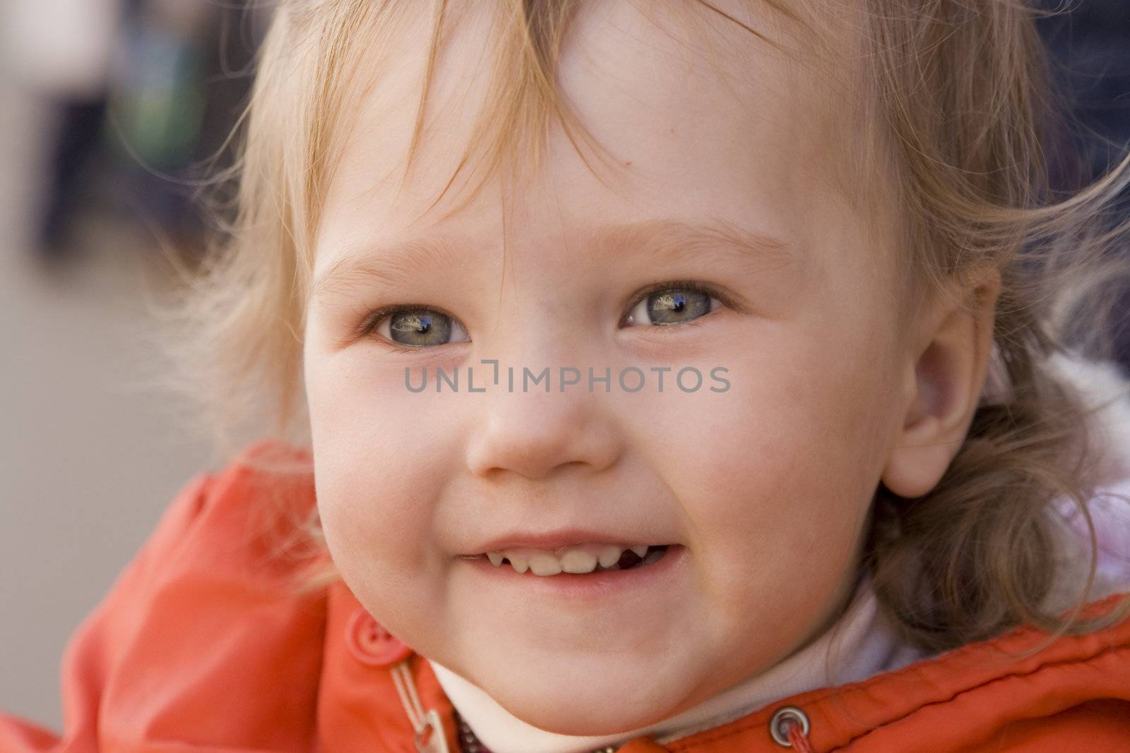 little smiling baby with curious eyes in orange