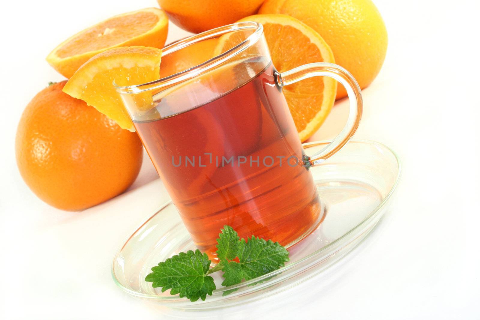 a cup of orange tea with fresh oranges and lemon balm