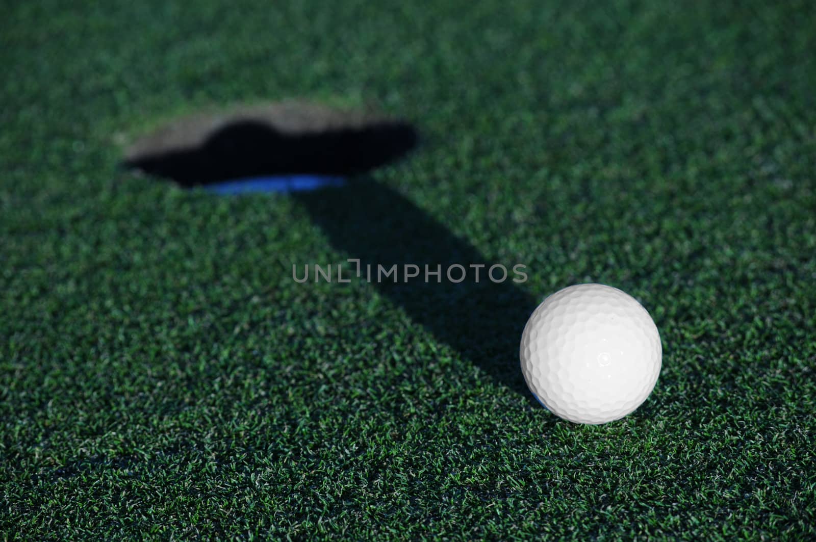 golf ball shadow striking cup on green