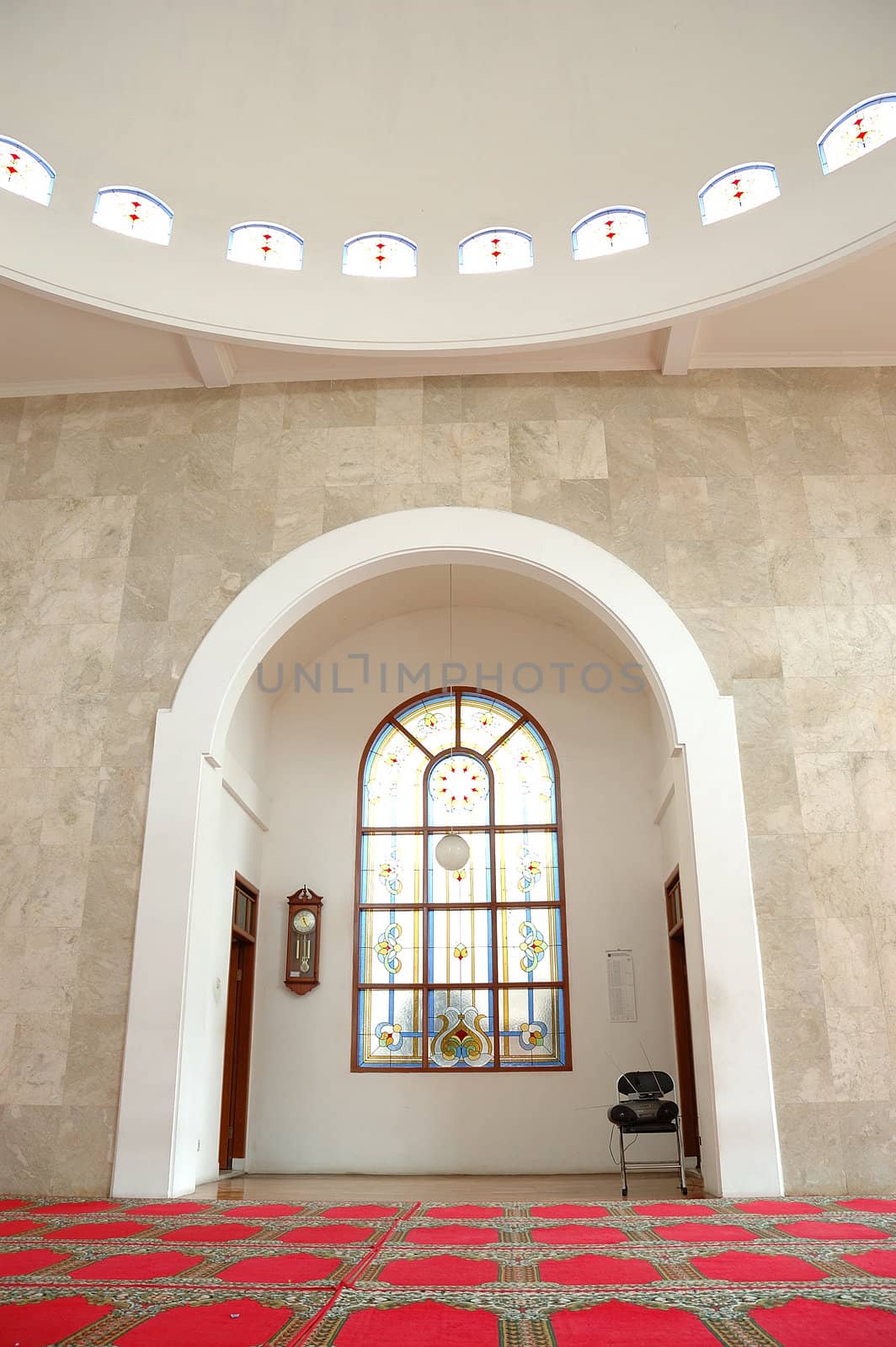 masjid hall with red carpet and white marble wall
