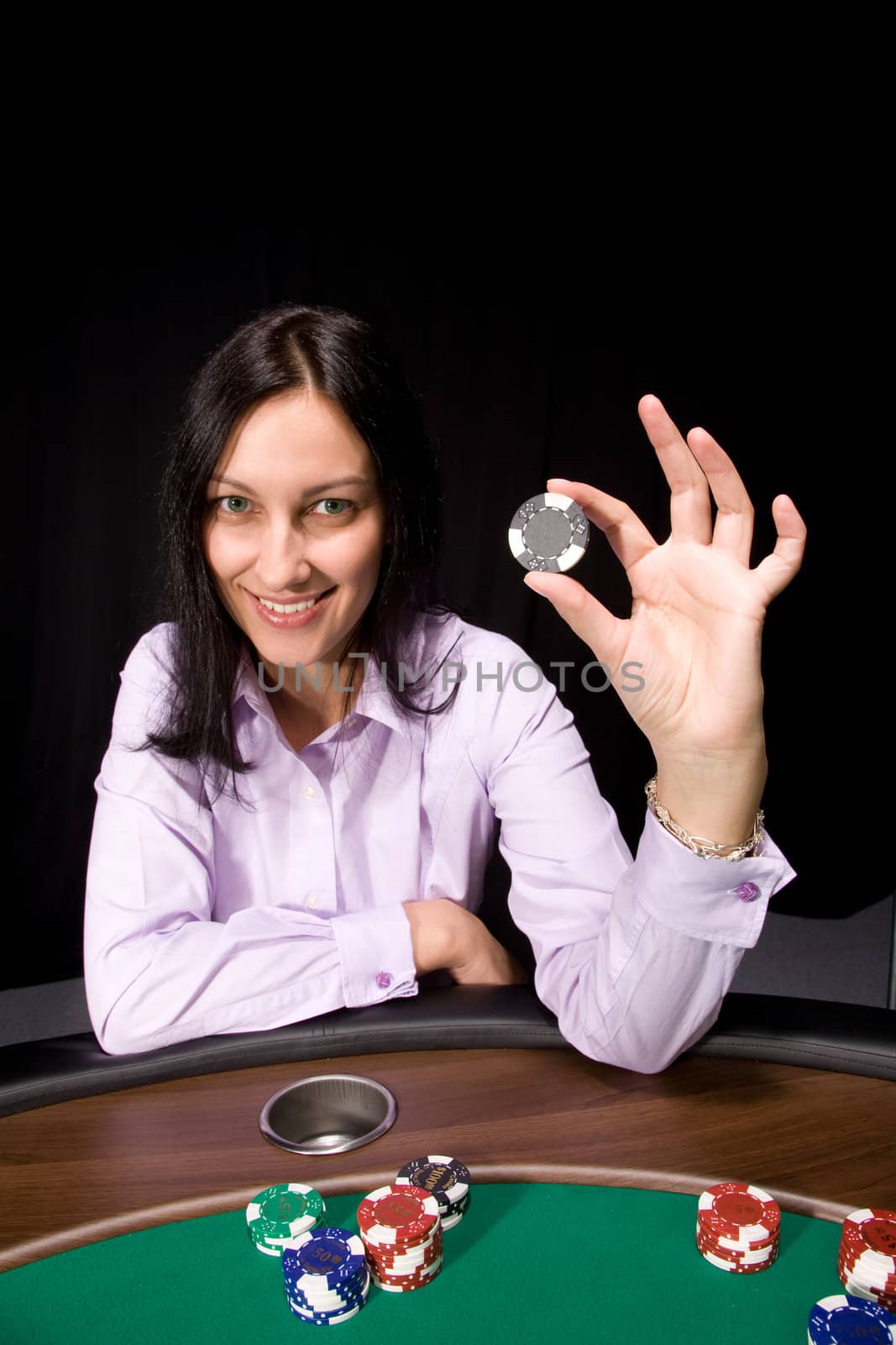 Pretty caucasian girl holds casino chip in hand over black