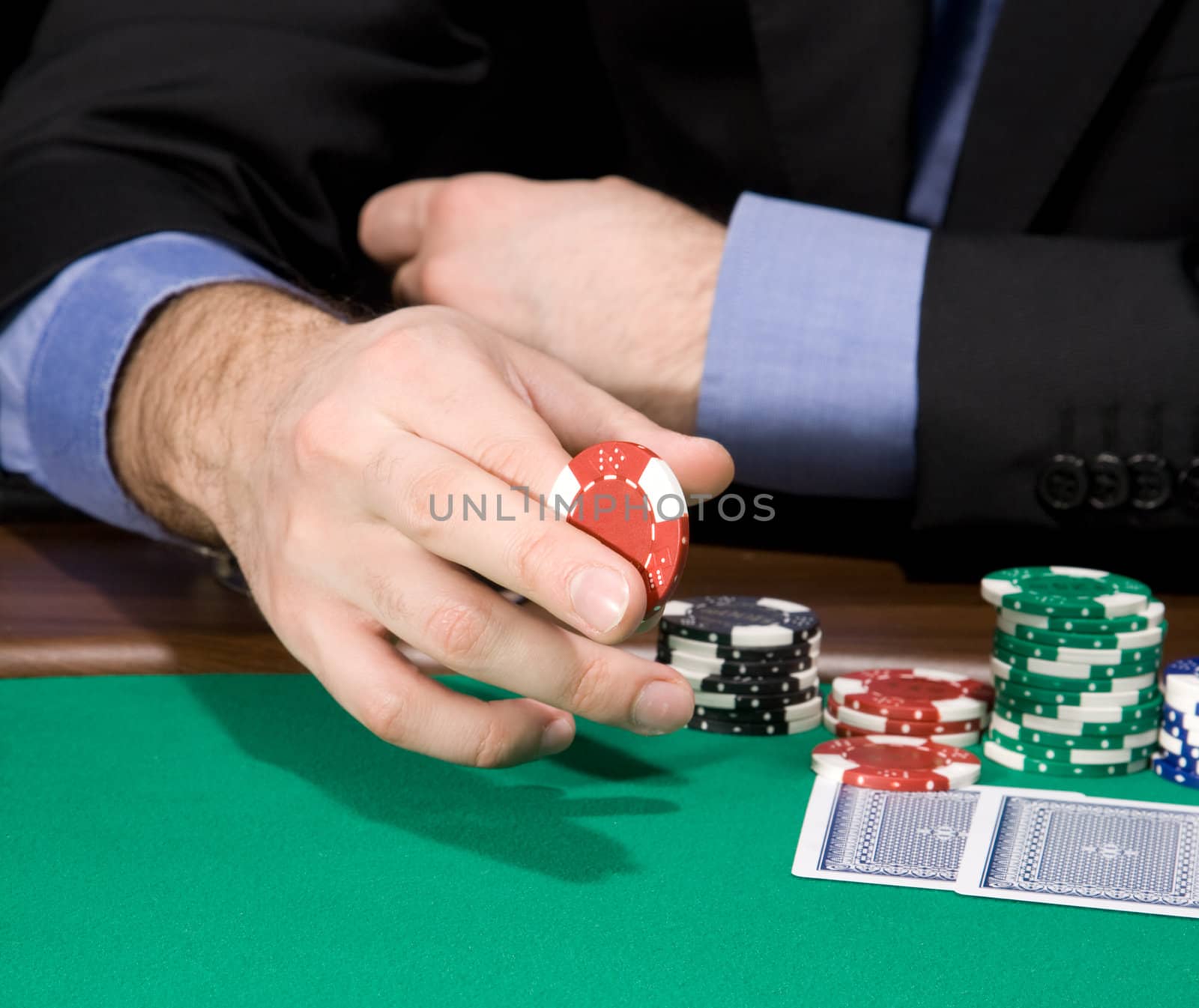 Hand of man holding casino chip over green felt