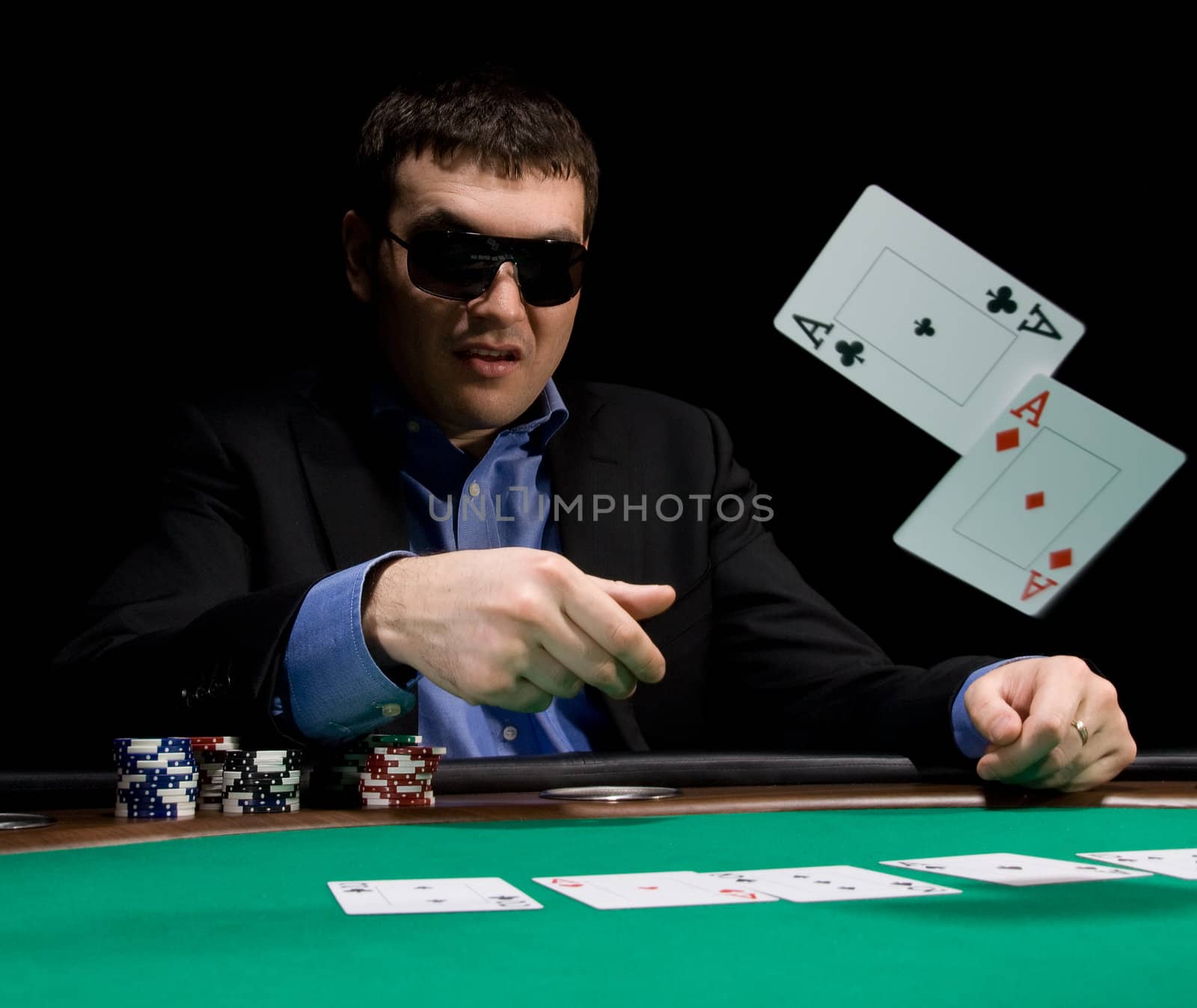 Stylish man in black suit folds two aces in casino poker at Las Vegas over black