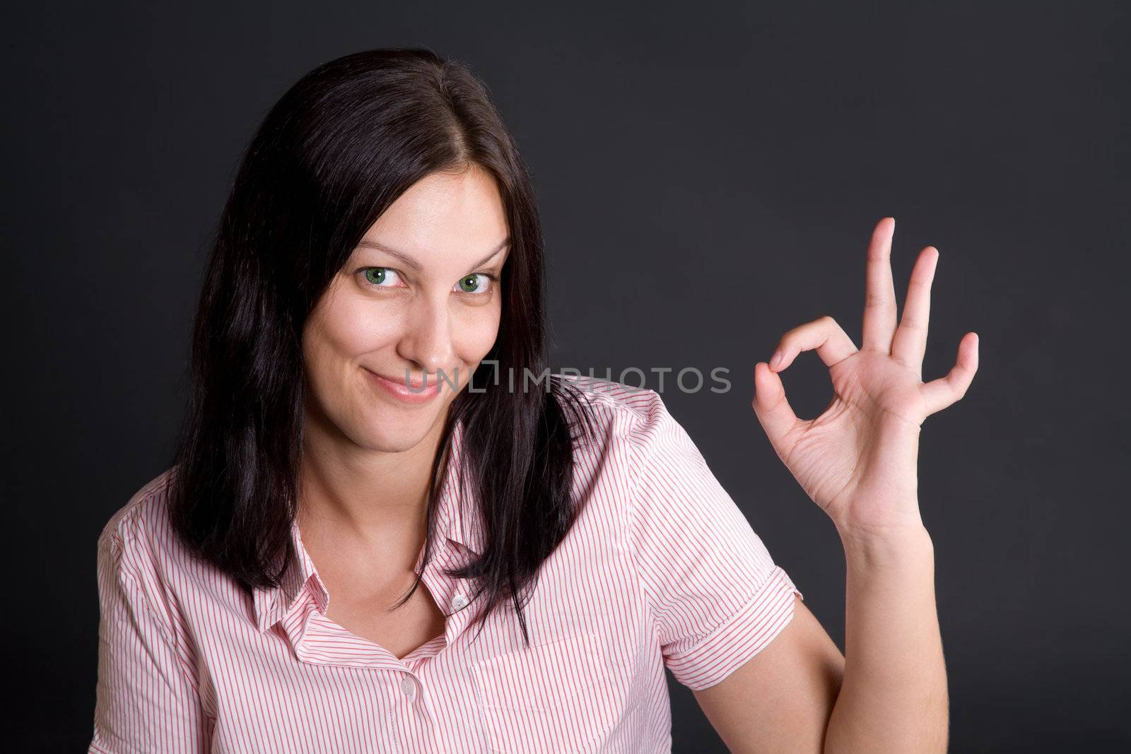 Smling girl showing ok sign with fingers over gray