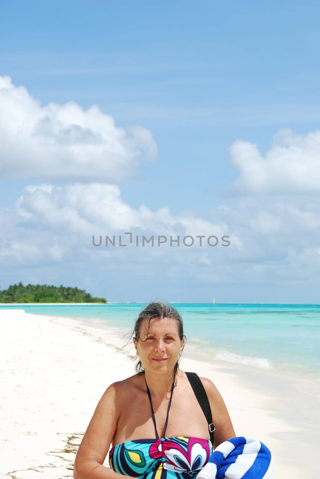 Beautiful senior woman walking on a tropical beach by luissantos84