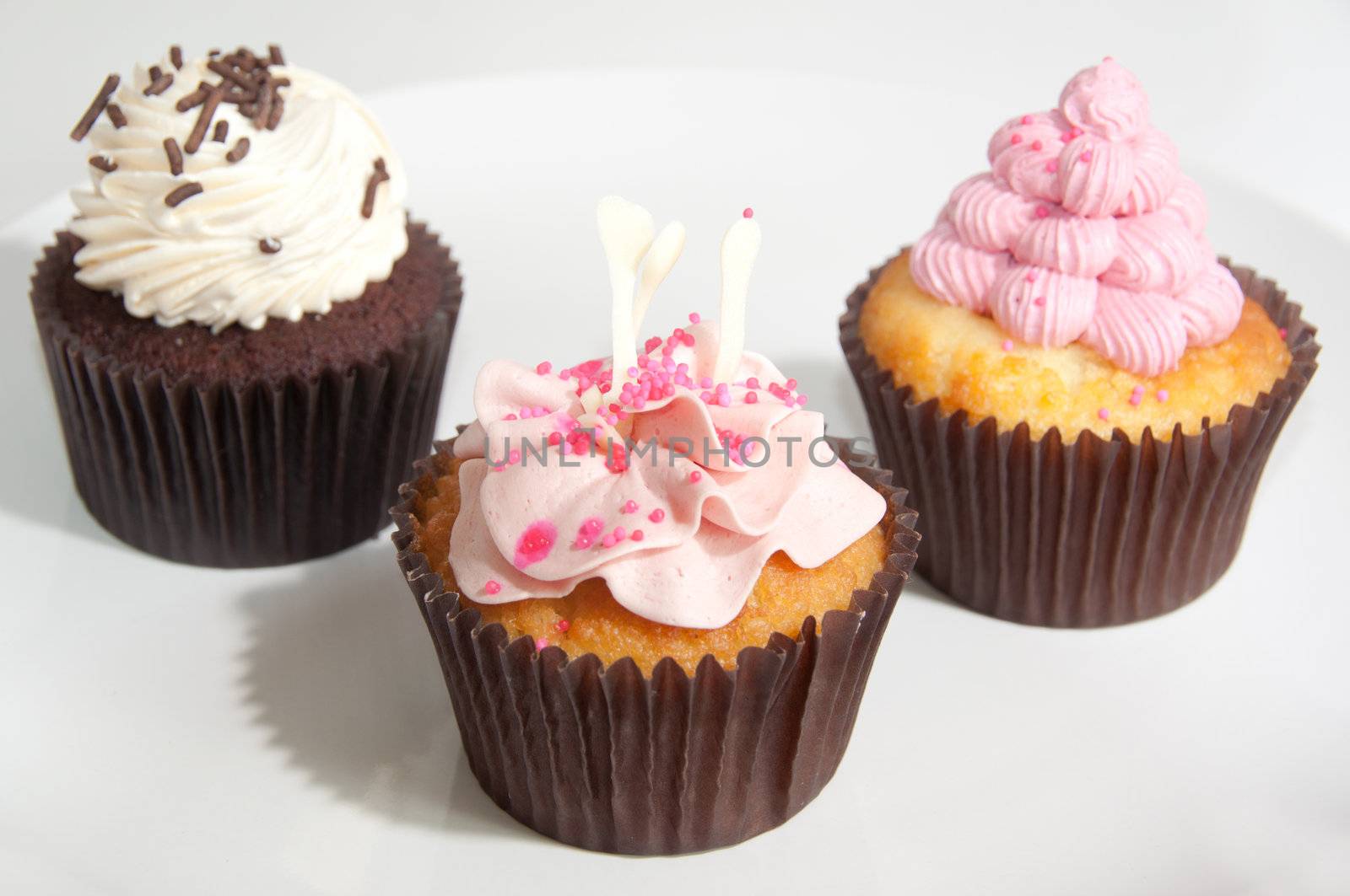 Various cupcakes decorated with frosting and dragees
