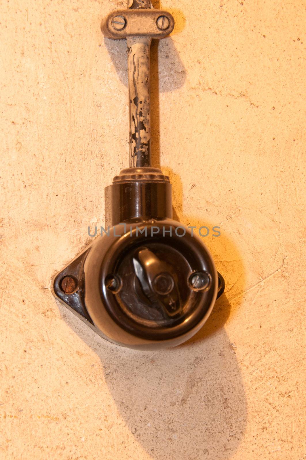 Old black lightswitch (bakelite) mounted on rough wall