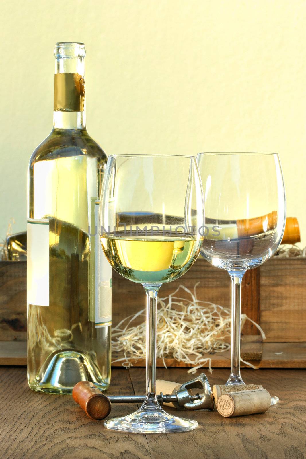 Still life of white wine bottle and glasses with crate in background