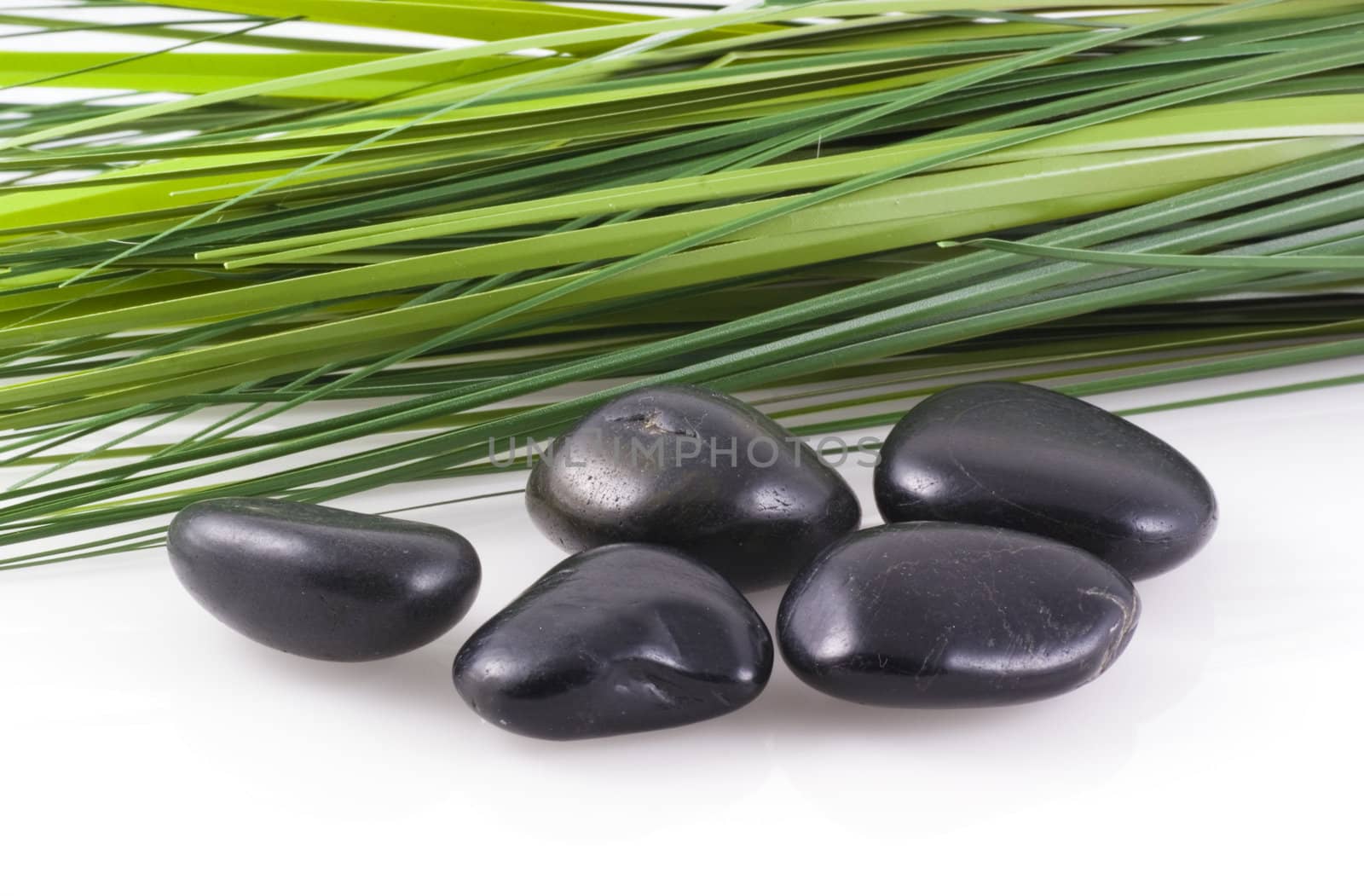 Zen stones with blades of grass in the back, isolated on white.