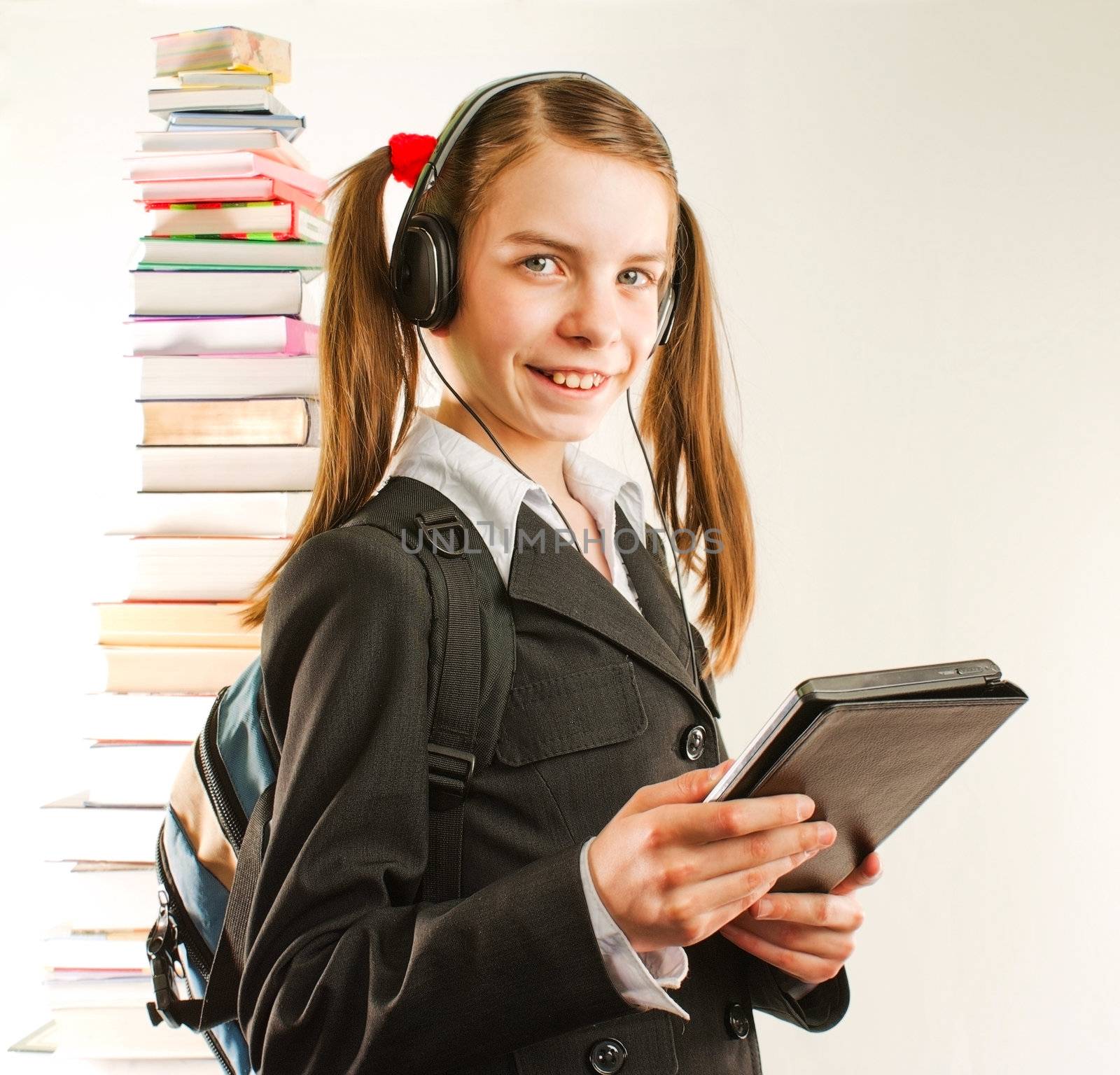 Teen girl with electronic book with a stack of printed books behind