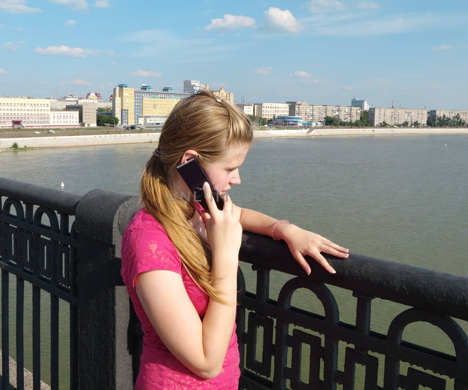  young girl speaks over telephone on city panorama back 