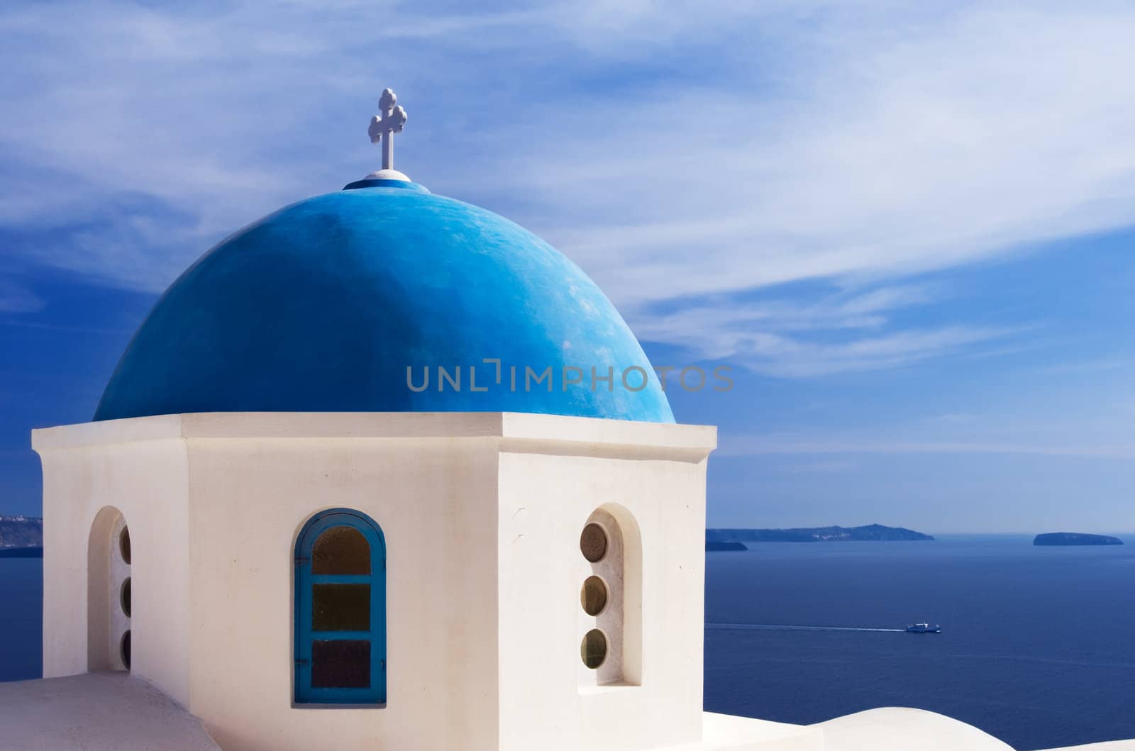 A church with a blue dome overlooks the spectacular caldera surrounding the beautiful island of Santorini, Greece