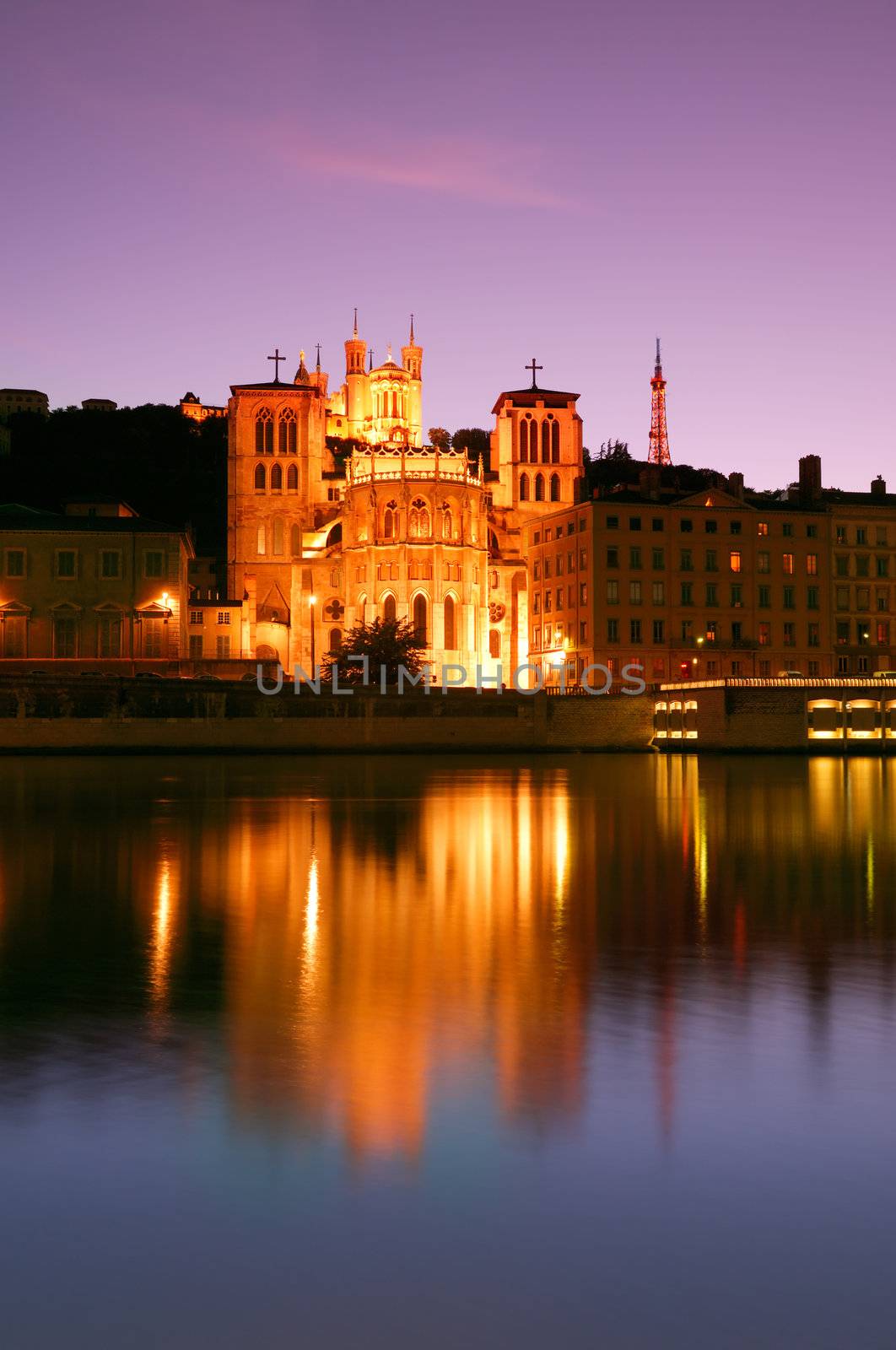 The Notre Dame de Fourviere basilica and the St. Jean cathedral both illuminated and reflected on the waters of the river Saone, in Lyon, France