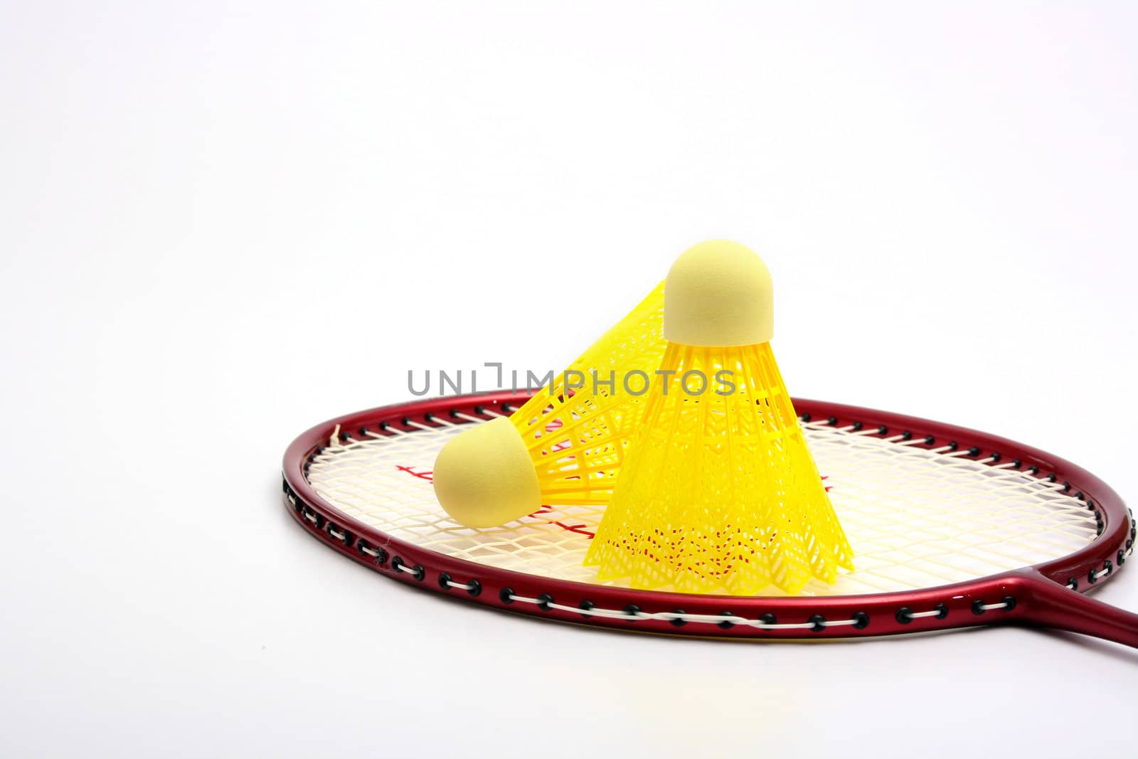 Yellow shuttlecock for badminton and a racket.