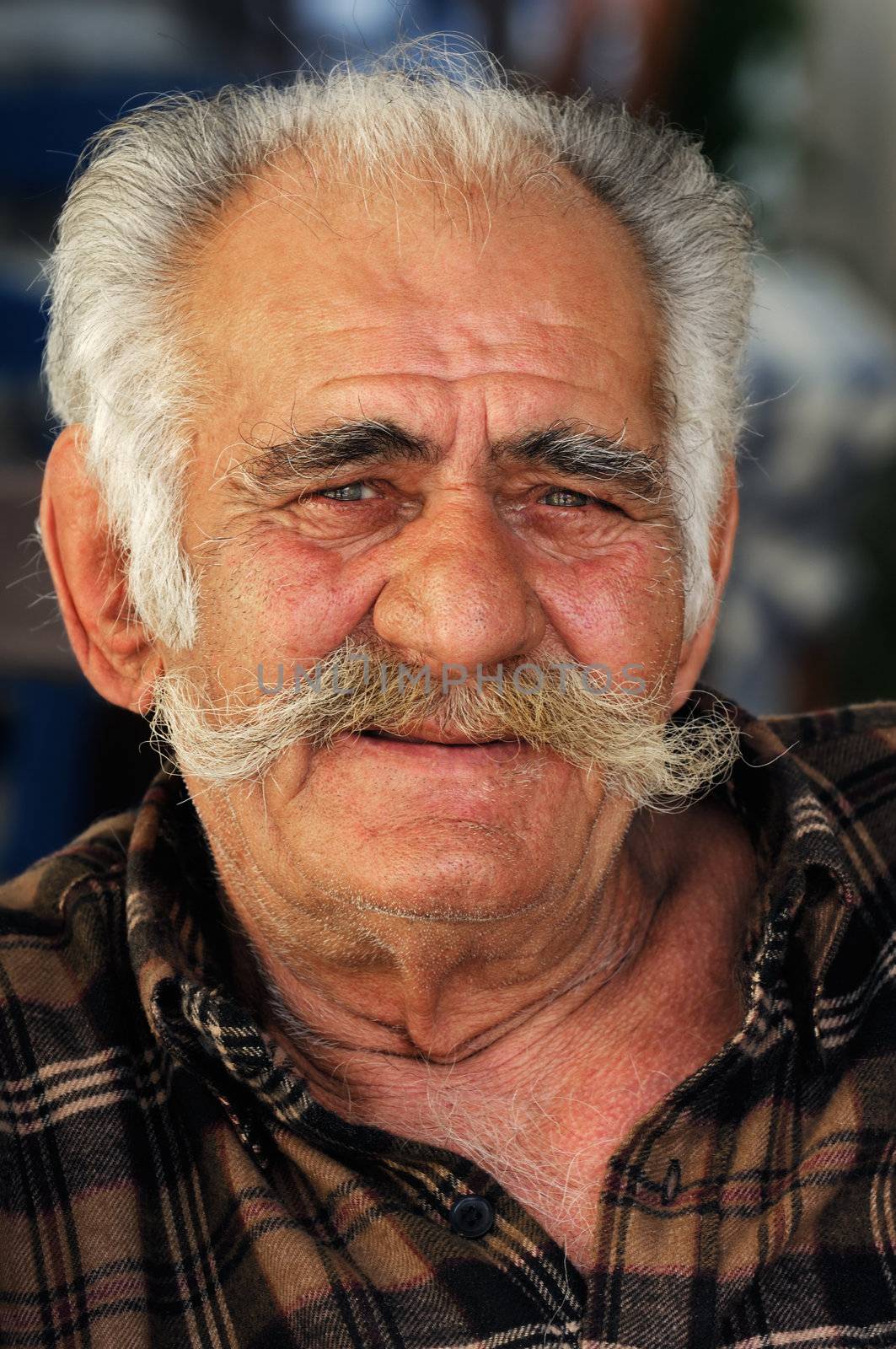 Portrait image of a senior Greek male with a big mustache looking at the camera