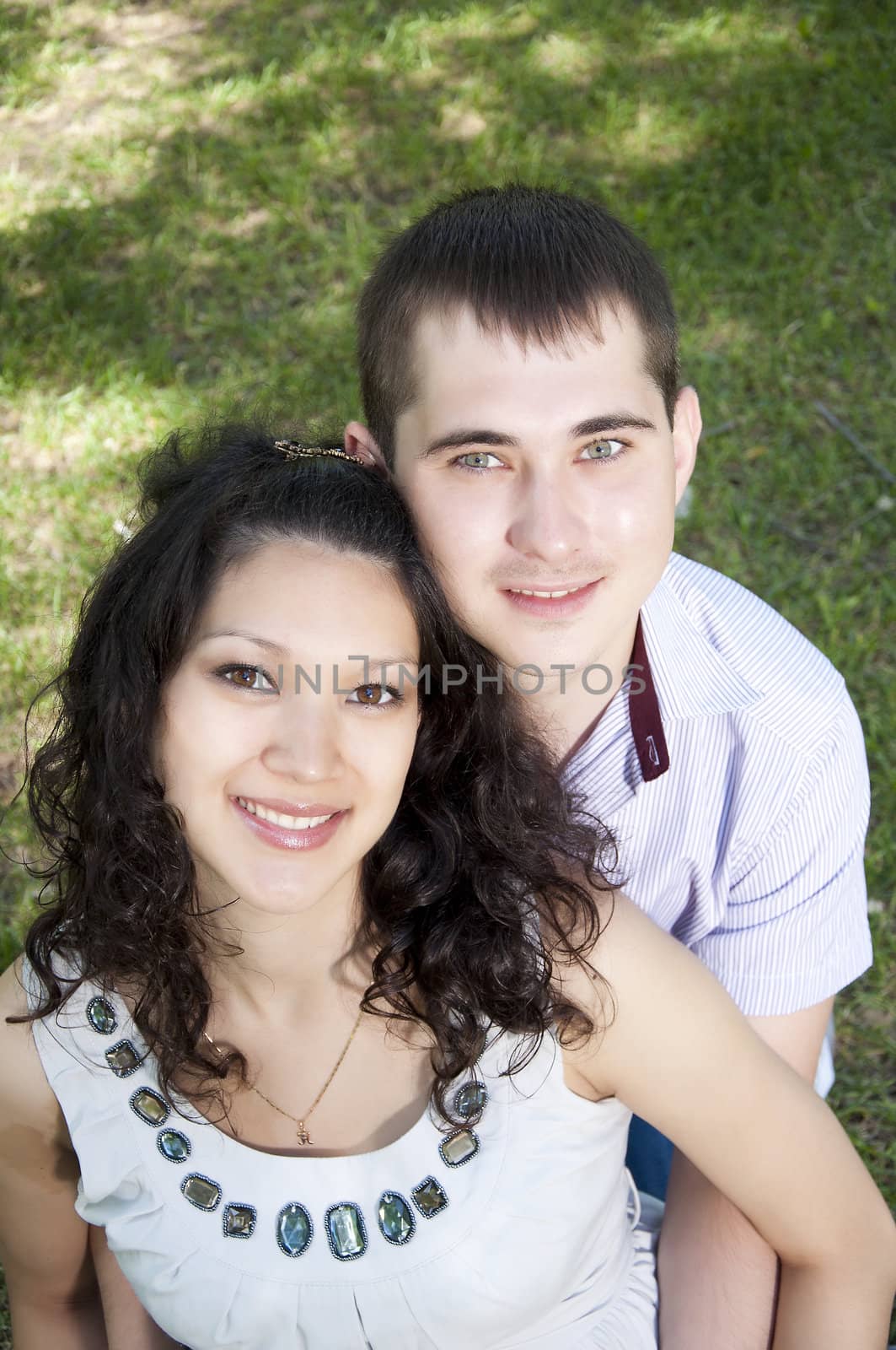 couple embraces in park, green grass background