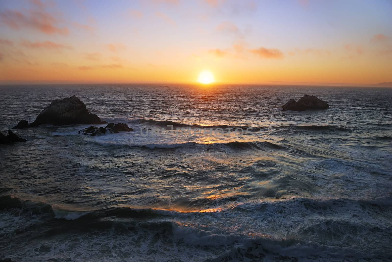 Sunset above the wavy Pacific as seen from the Ocean Beach in San Francisco, California.