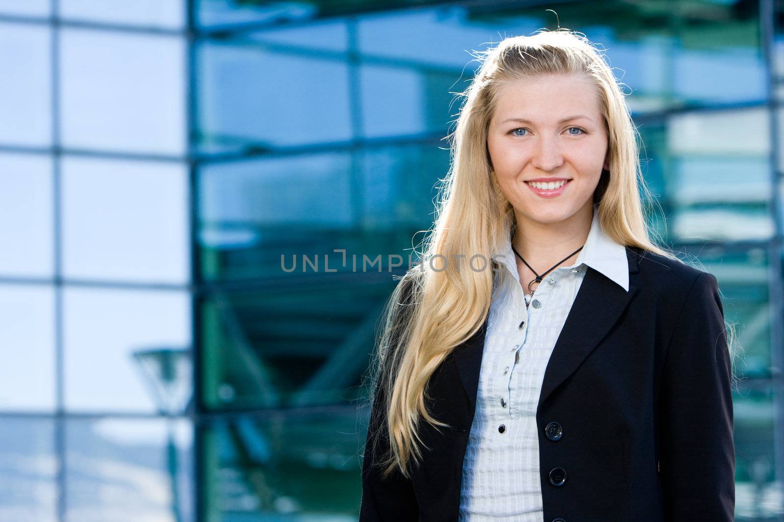 Beautiful blonde girl as business woman in front of office building