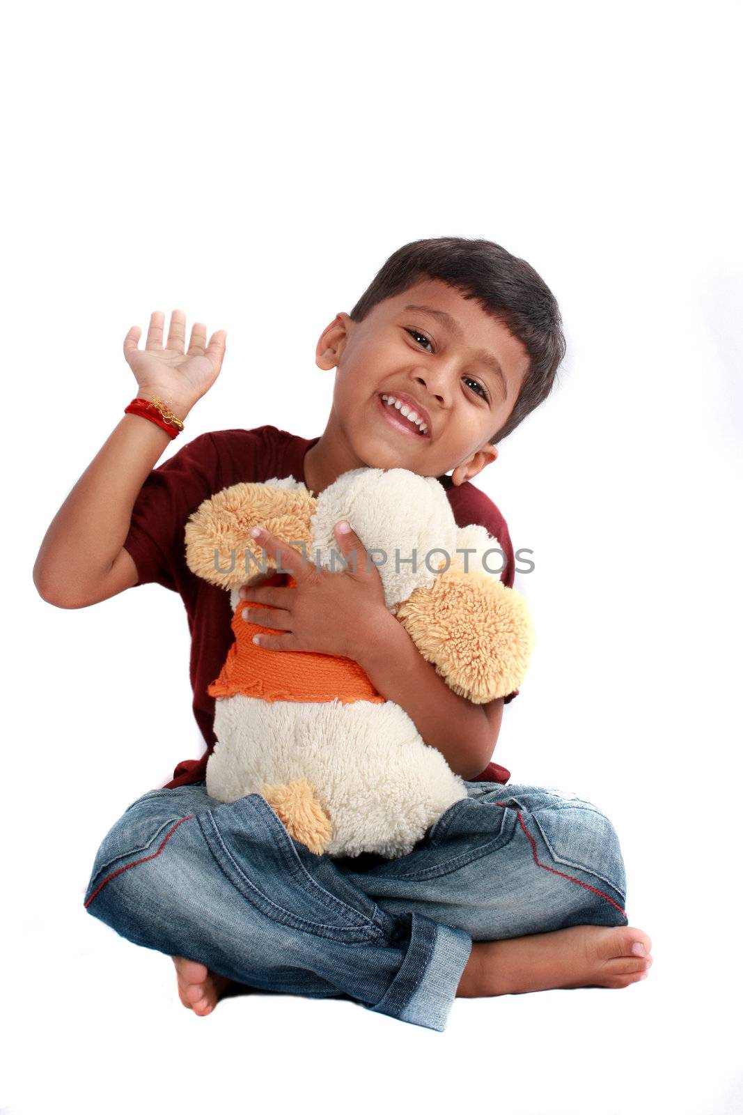 A cute Indian boy happy with his stuffed toy, on white studio background.