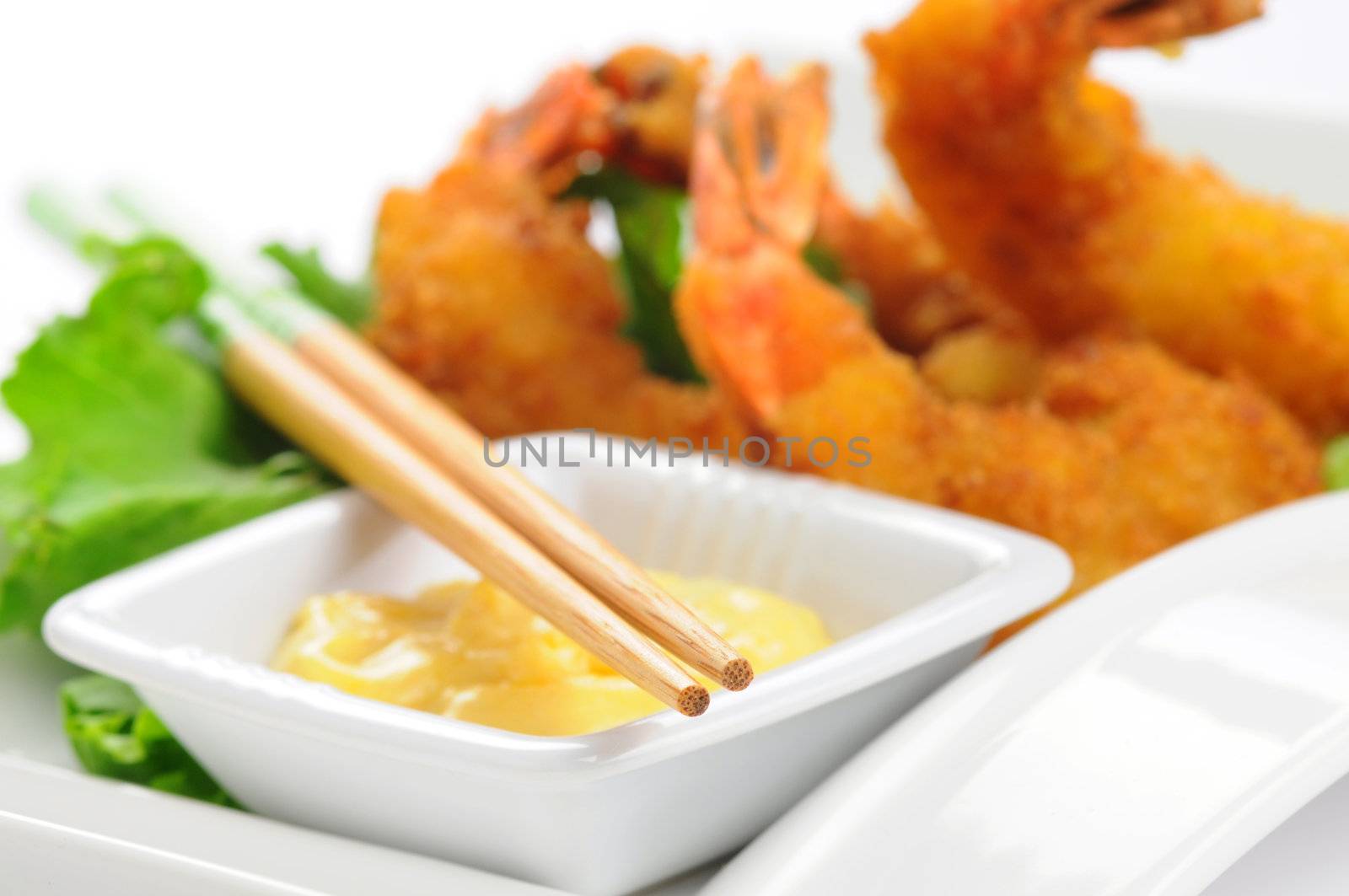 Closeup of chopsticks with an oriental meal in the background.